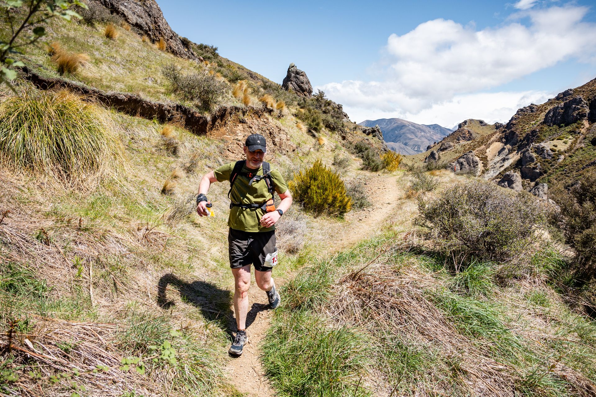 A man is running on a trail in the mountains.