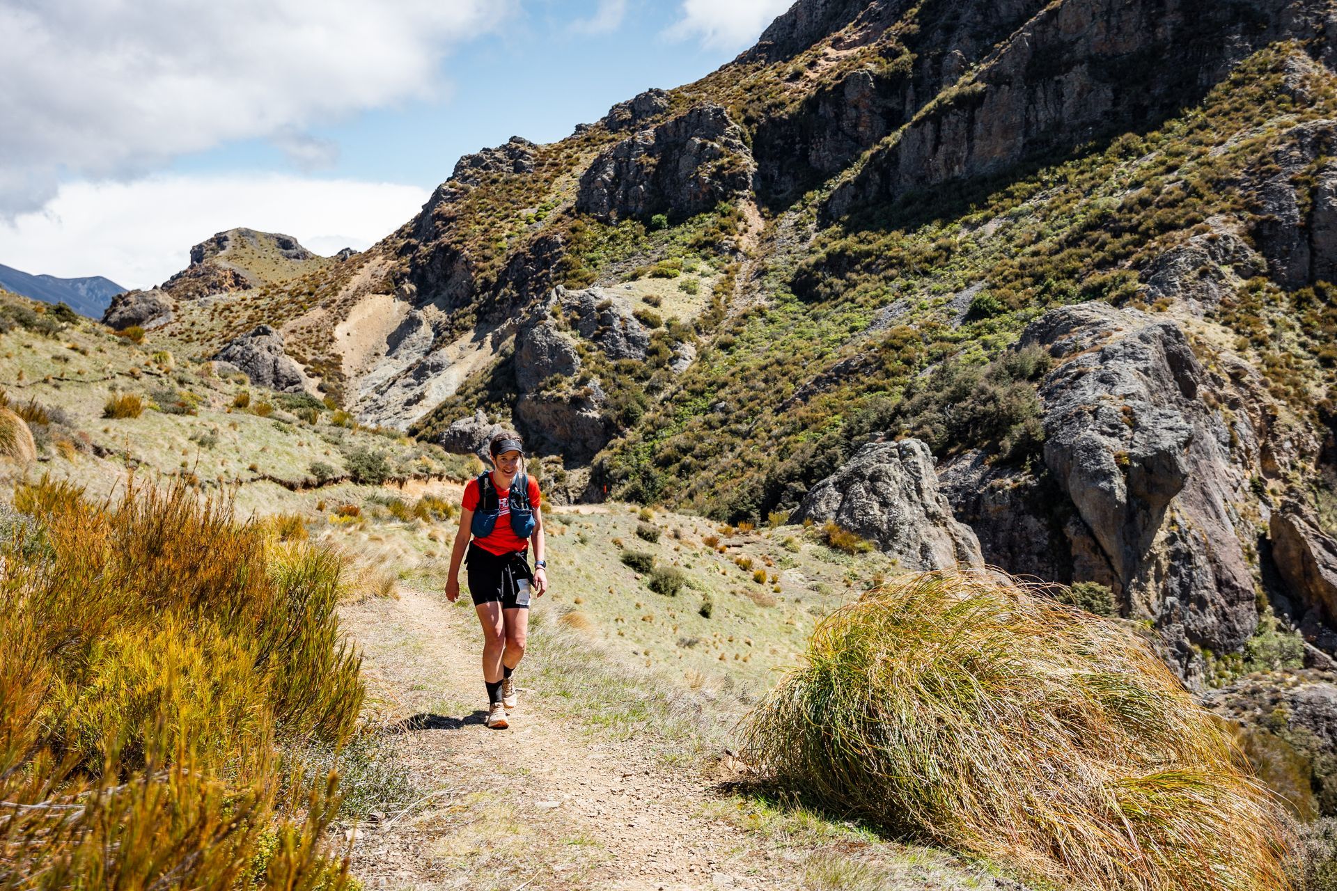A man is walking down a dirt path in the mountains.
