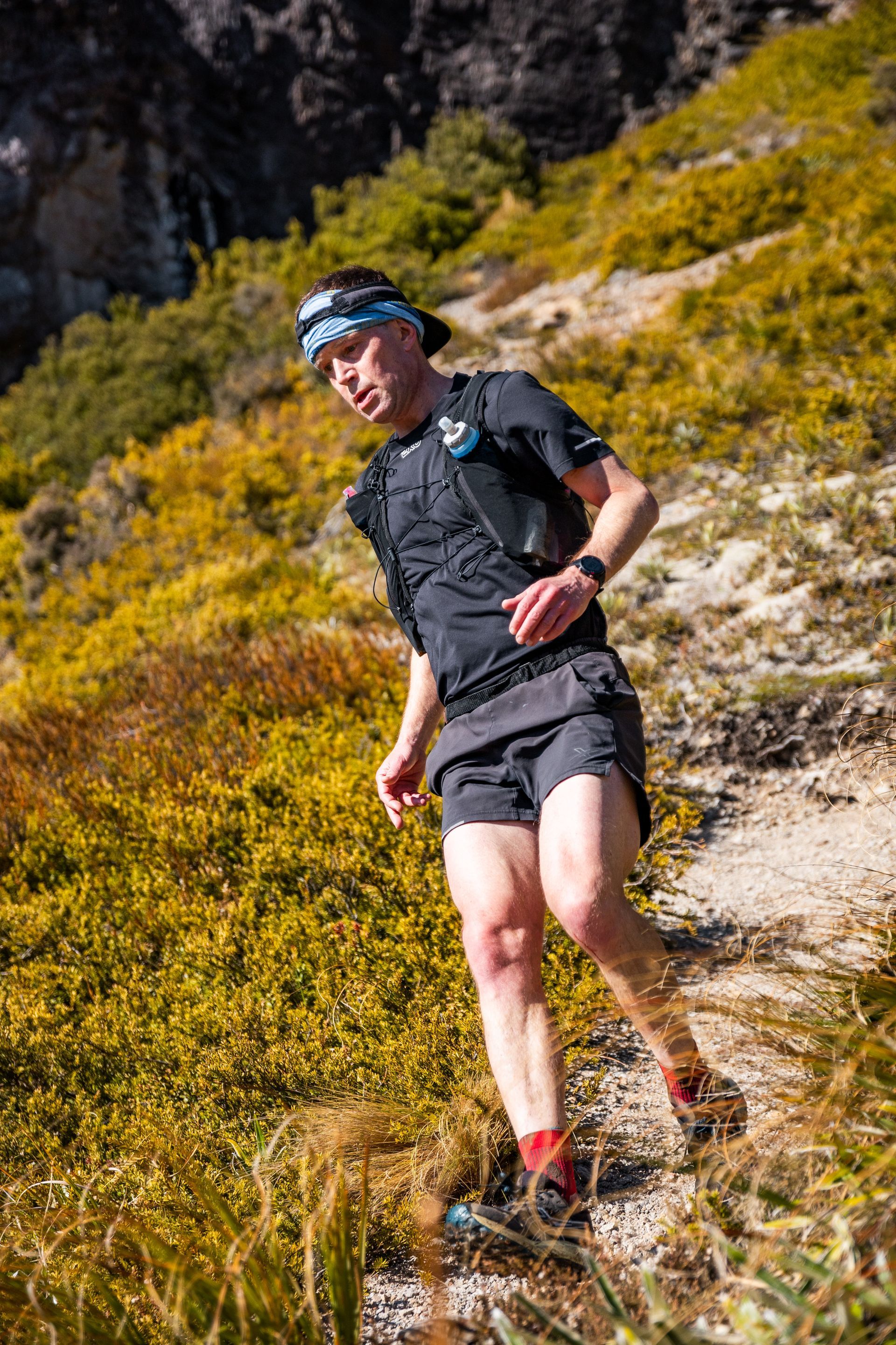 A man is running on a trail in the mountains.