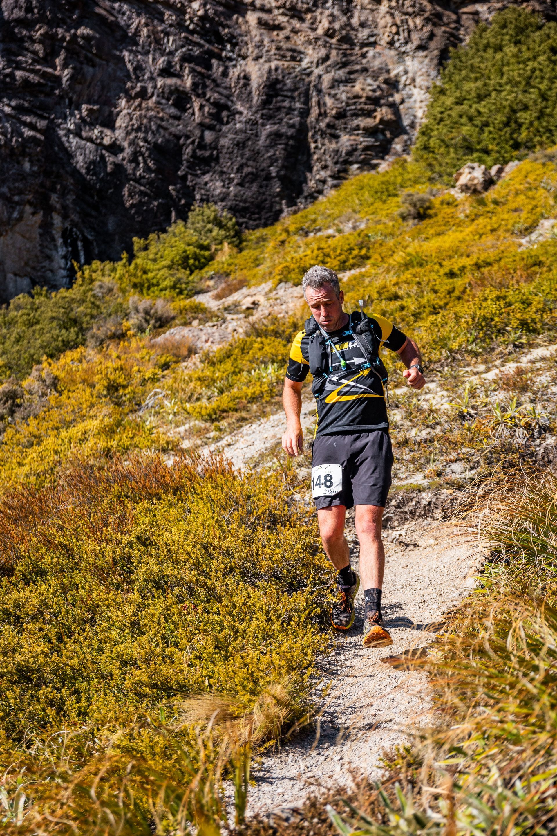A man is running on a trail in the mountains.