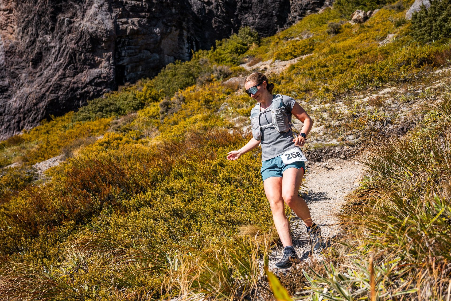 A woman is running up a hill on a trail.