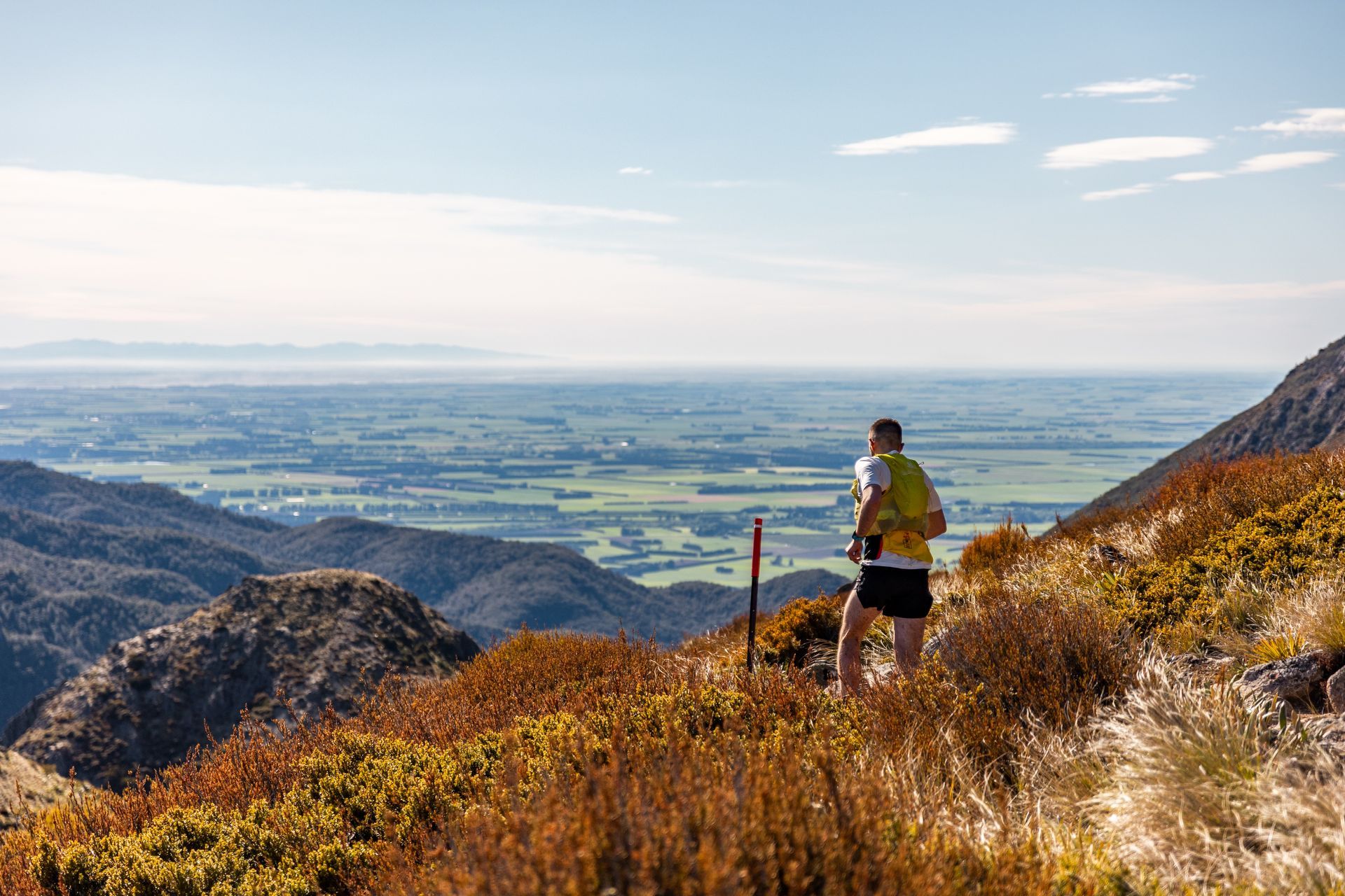 A man is standing on top of a mountain looking out over a valley.