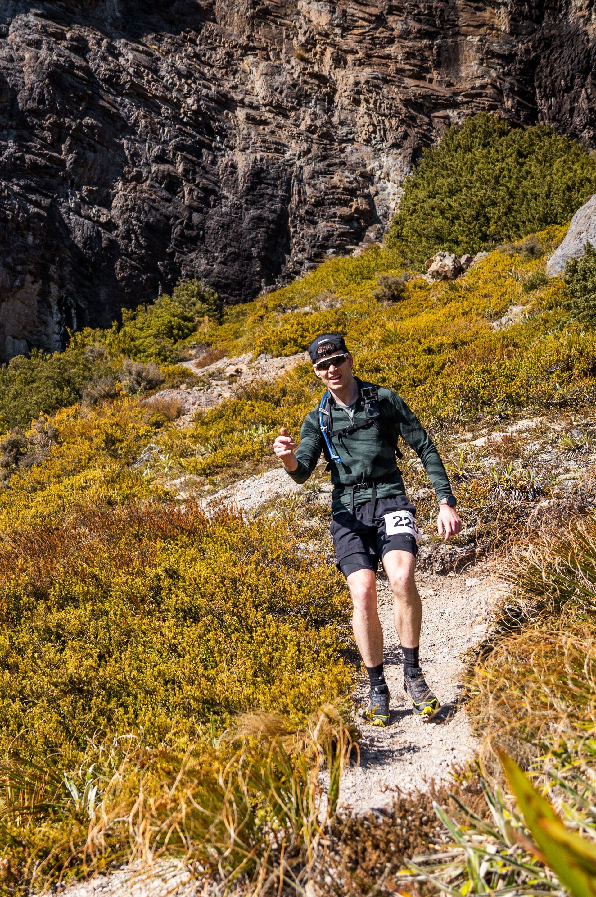 A man is walking down a trail in the mountains.