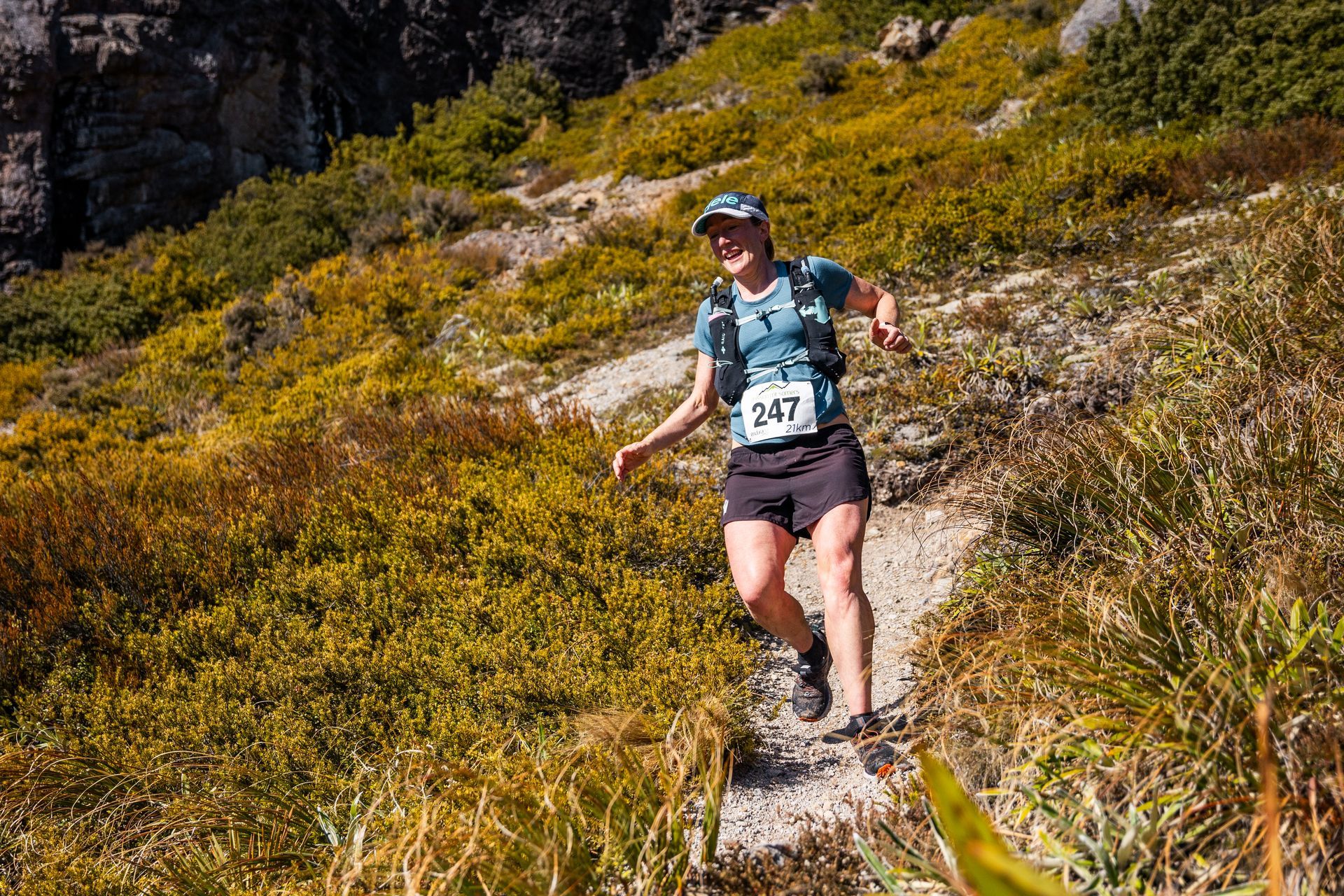 A woman is running on a trail in the mountains.