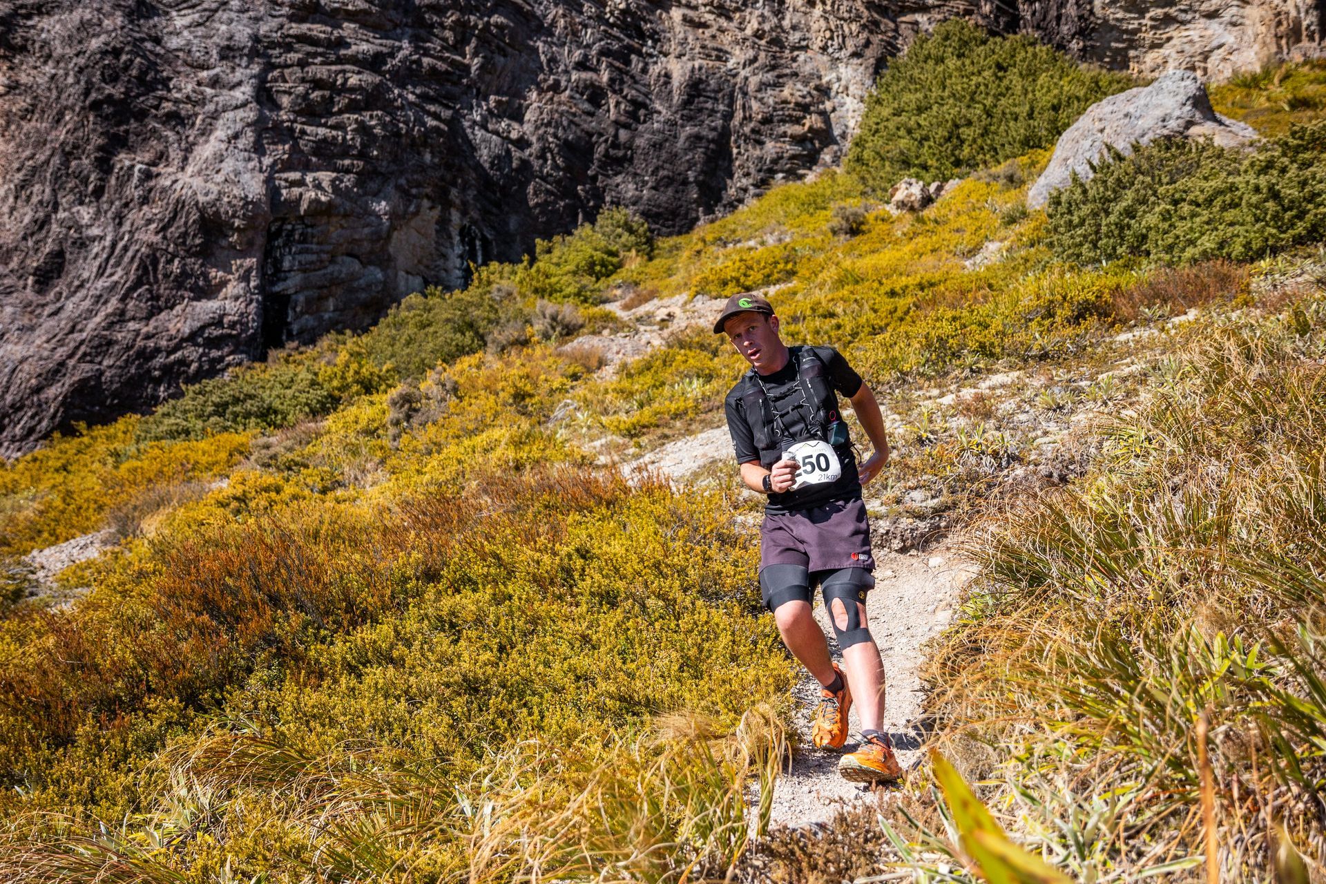 A man is running on a trail in the mountains.