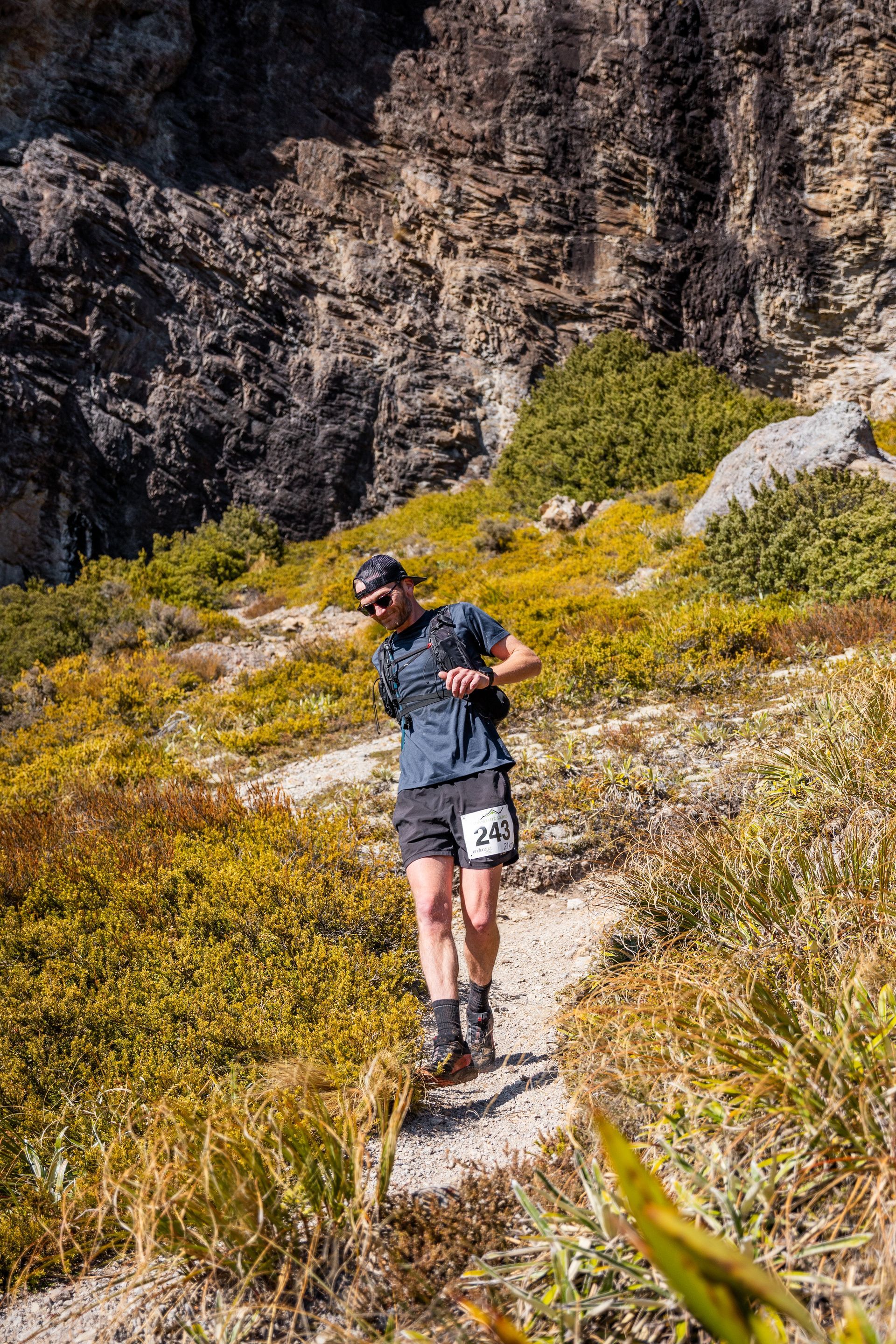A man is running on a trail in the mountains.