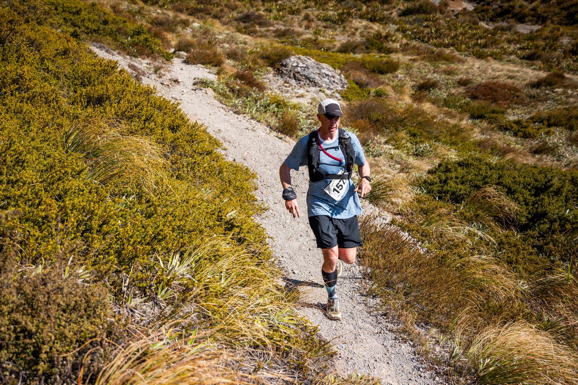 A man is running down a dirt path in the mountains.