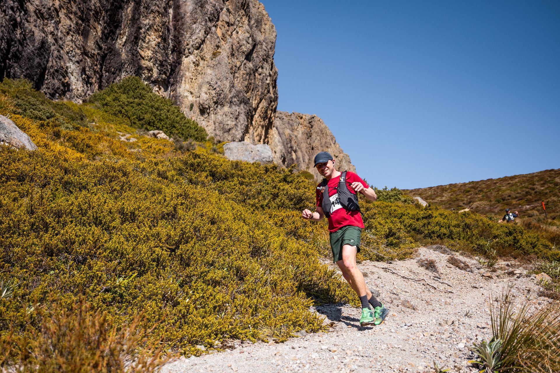 A man is running down a dirt path in the mountains.
