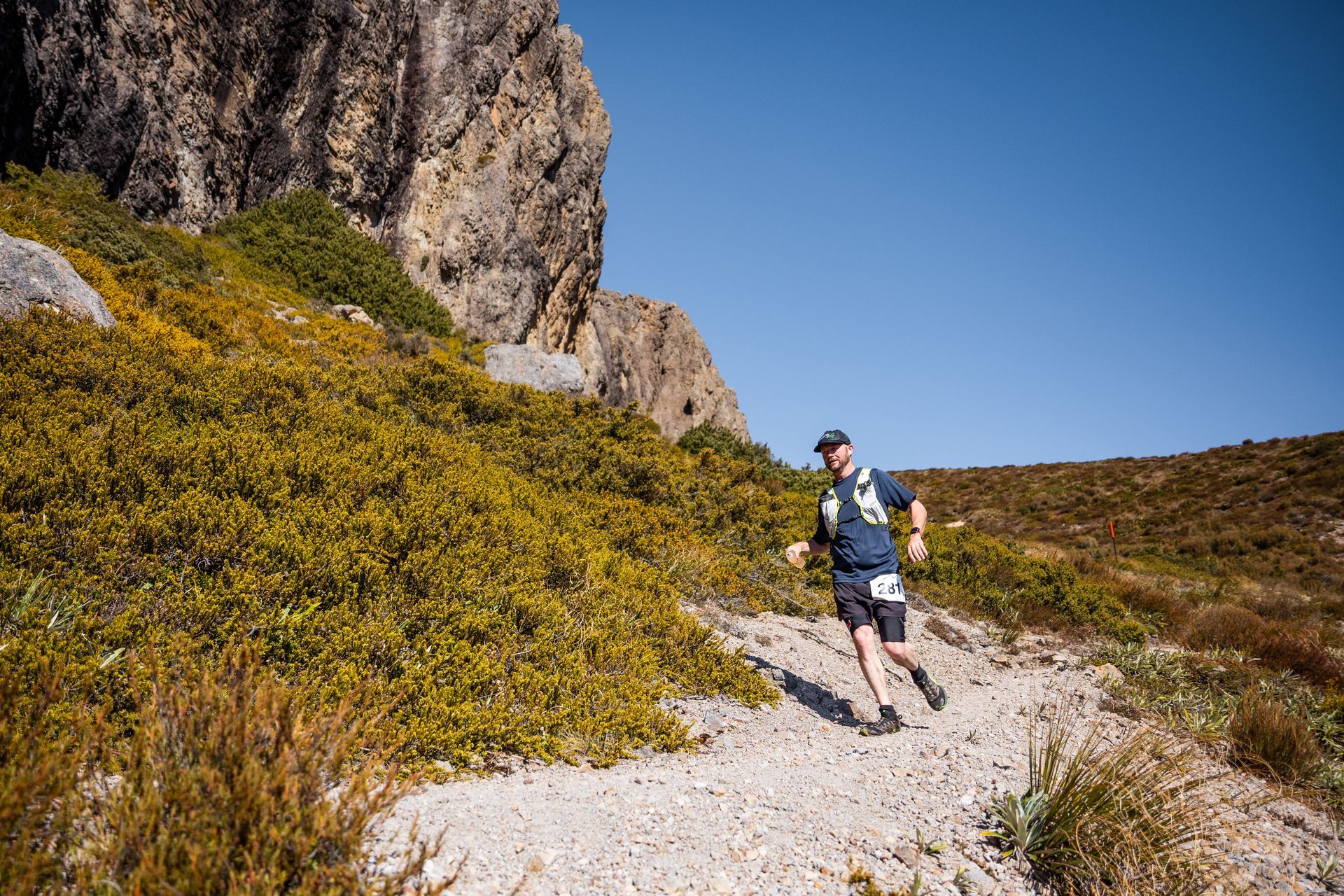 A man is running on a dirt path in the mountains.