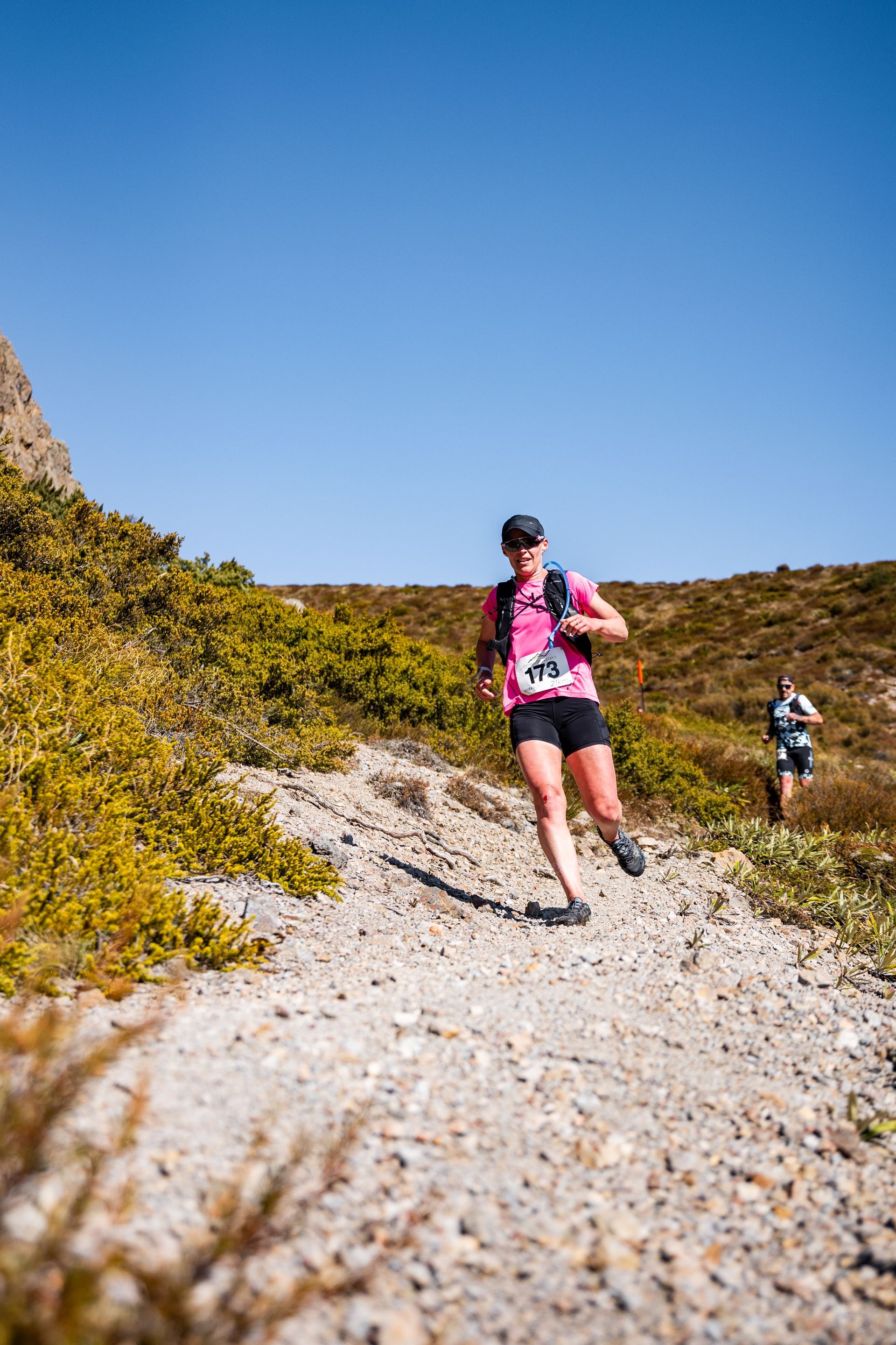 A woman is running down a dirt trail.