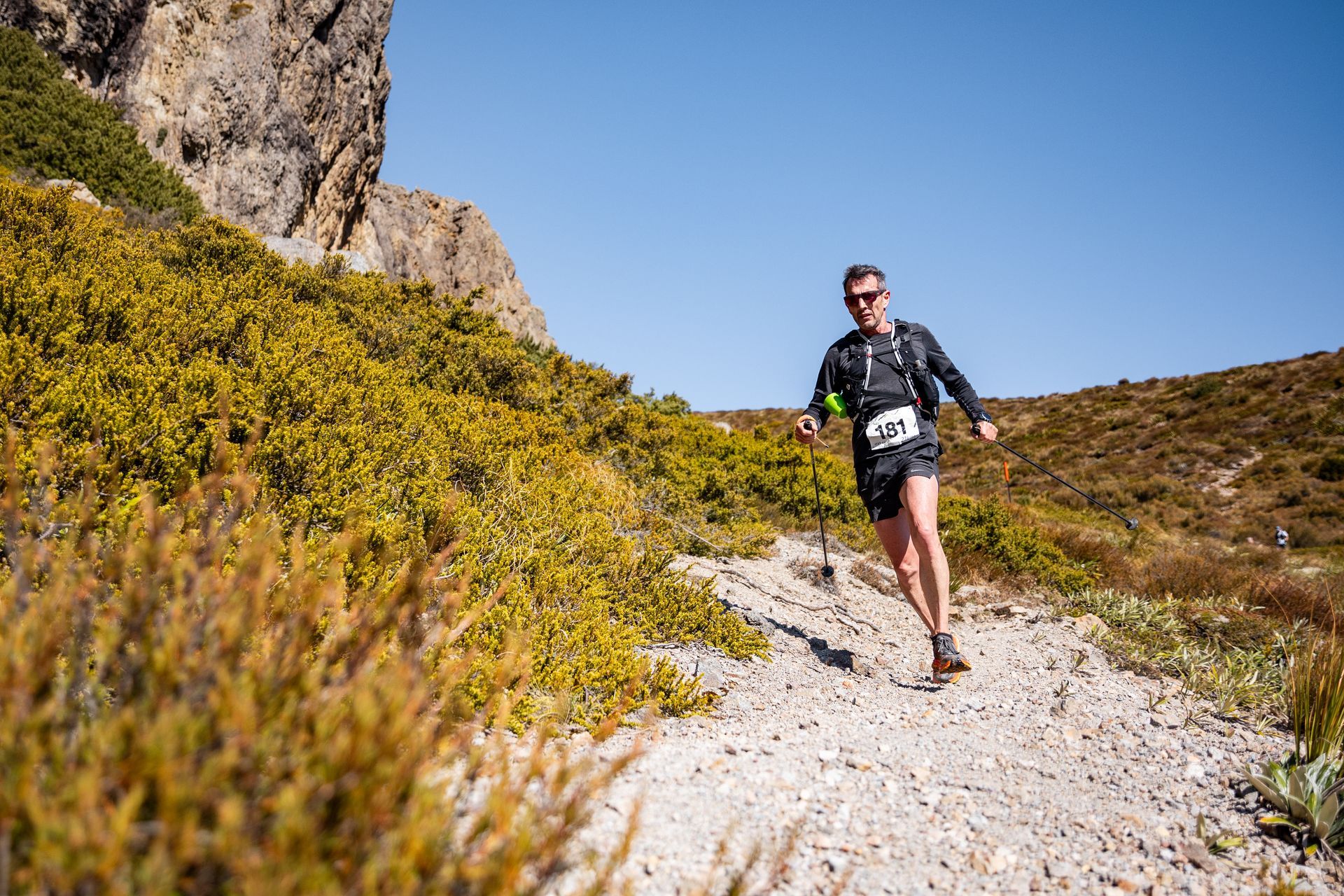 A man is running on a dirt path in the mountains.