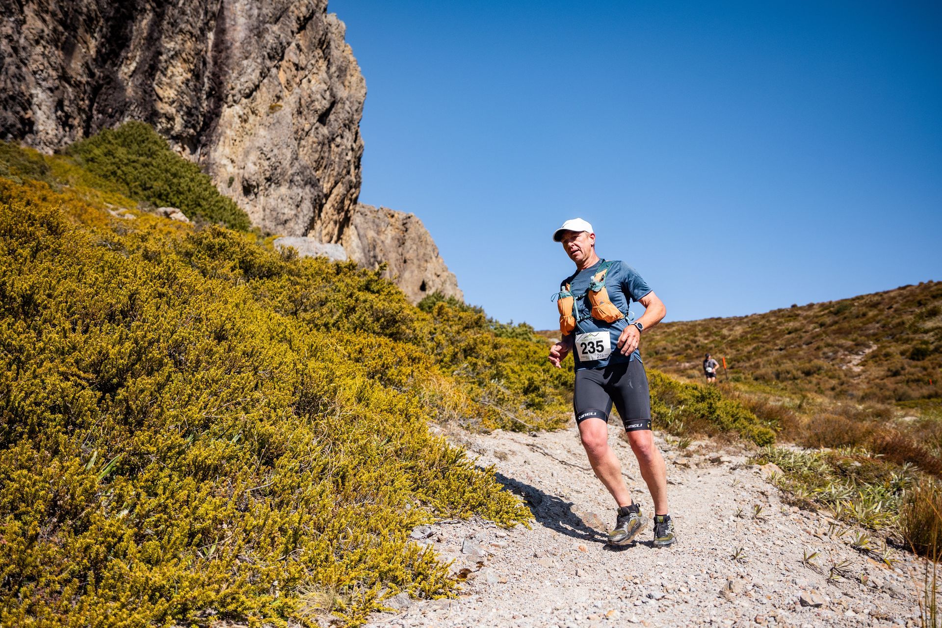 A man is running on a dirt path in the mountains.