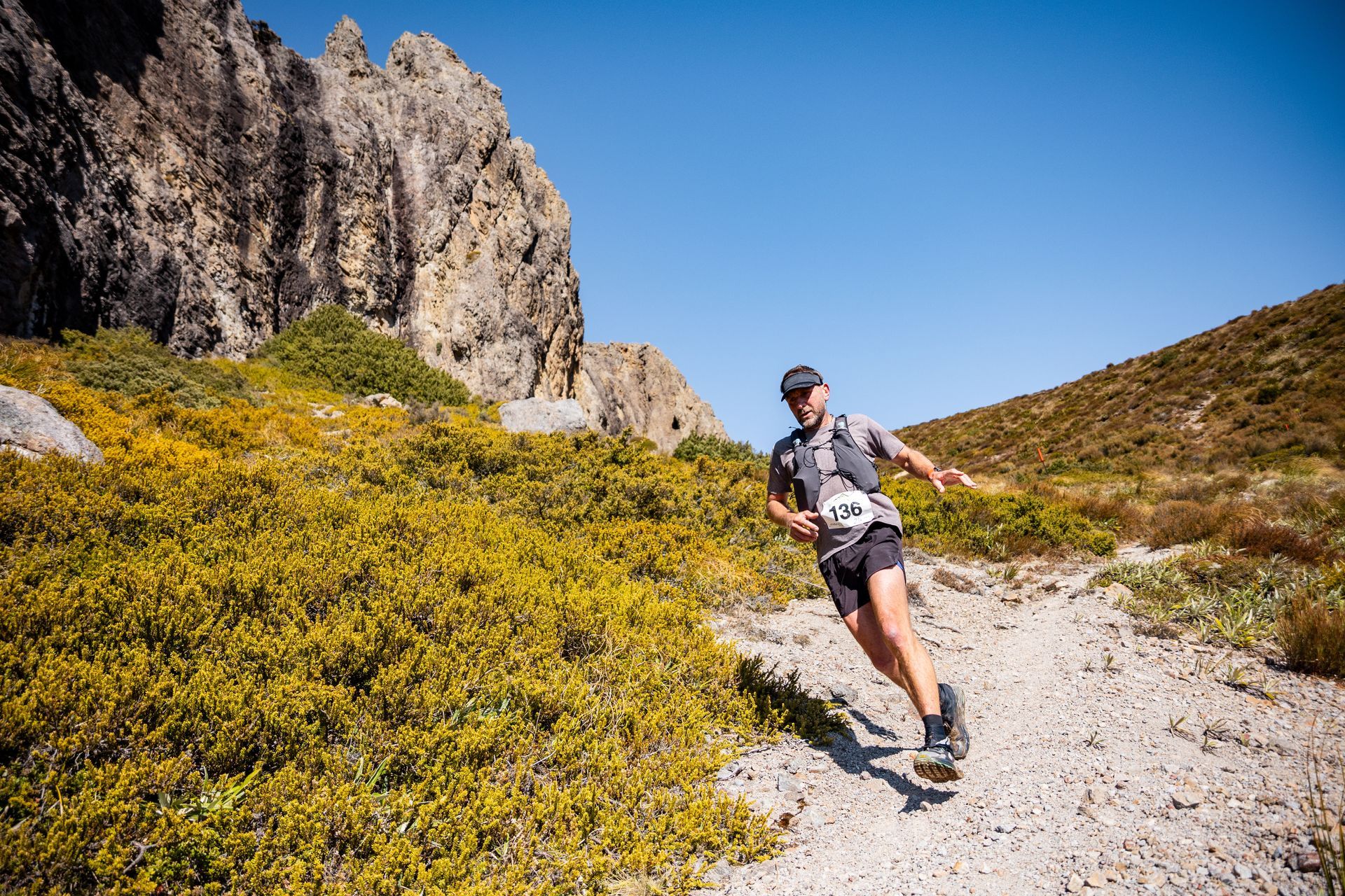 A man is running down a dirt path in the mountains.