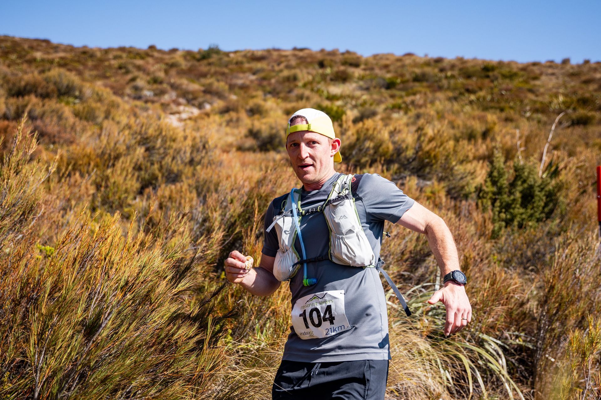 A man is running in a field with a number 104 on his shirt.