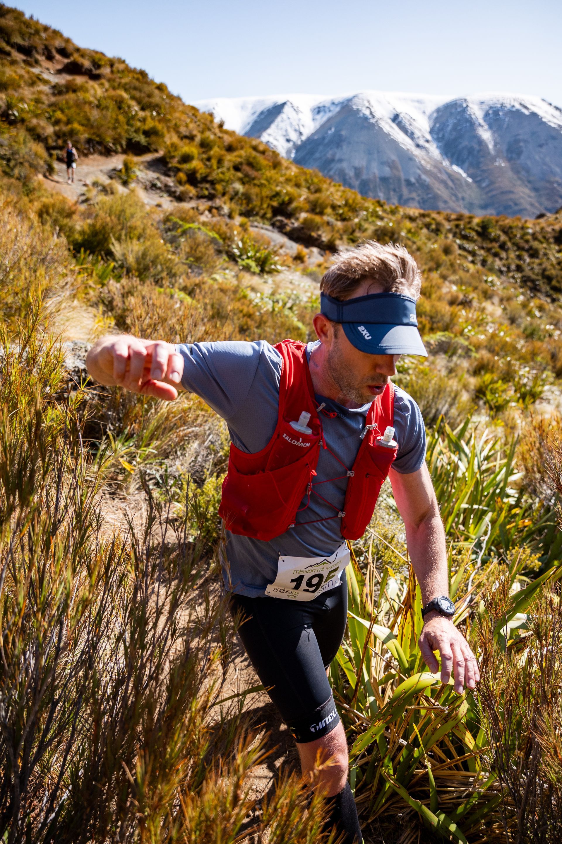 A man is running on a trail in the mountains.