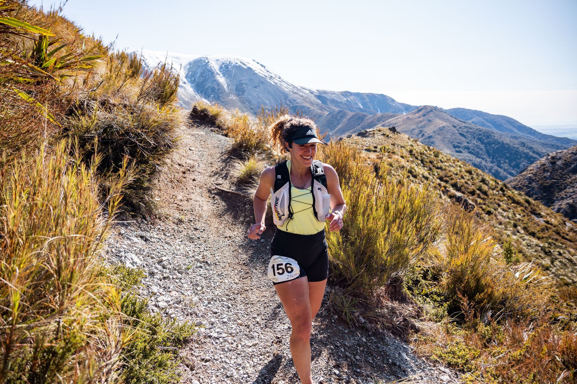 A woman is running on a trail in the mountains.