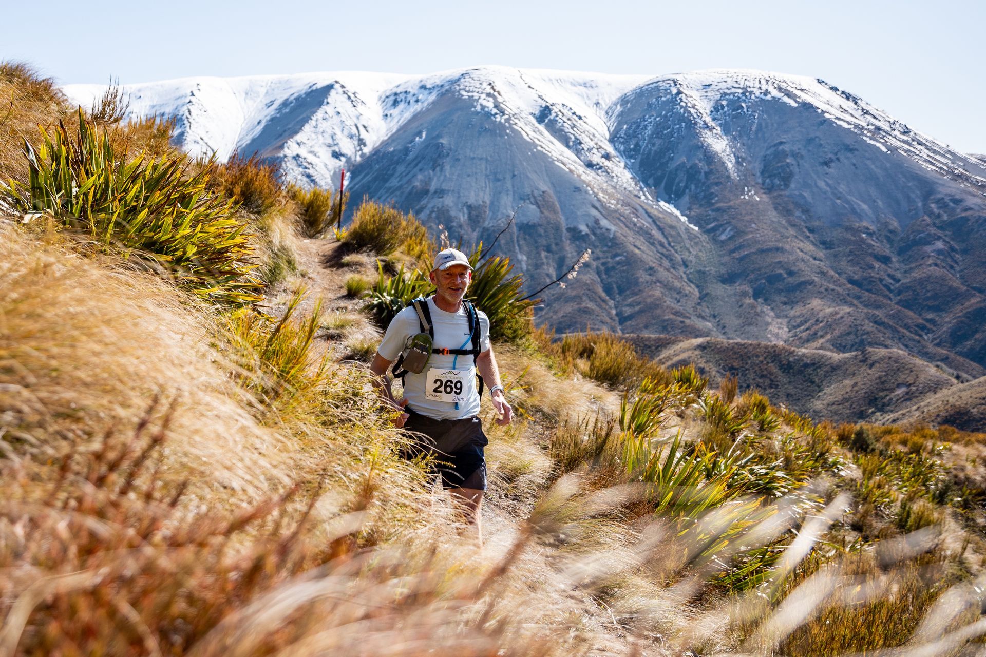 A man is running on a trail in the mountains.