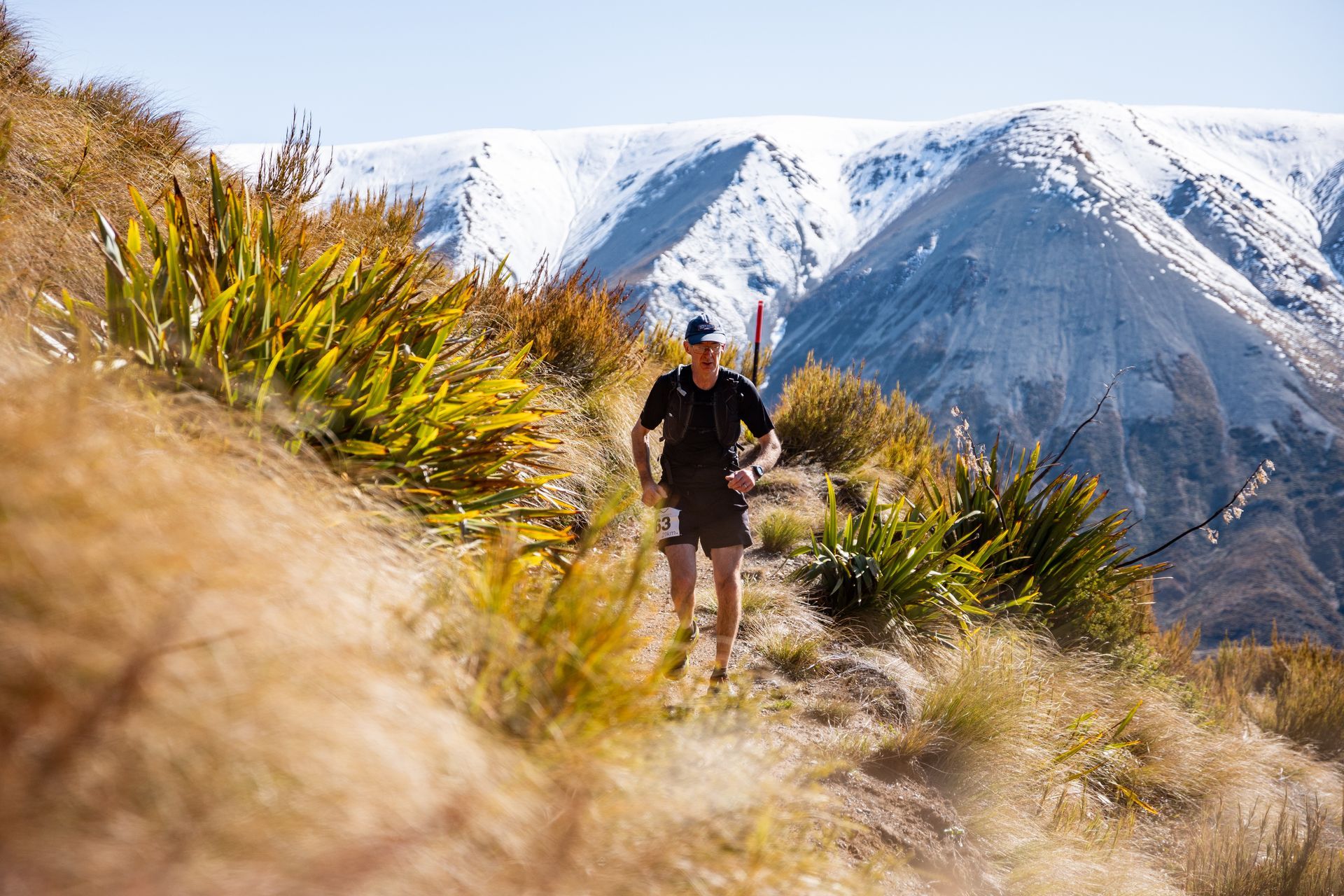 A man is running on a trail in the mountains.