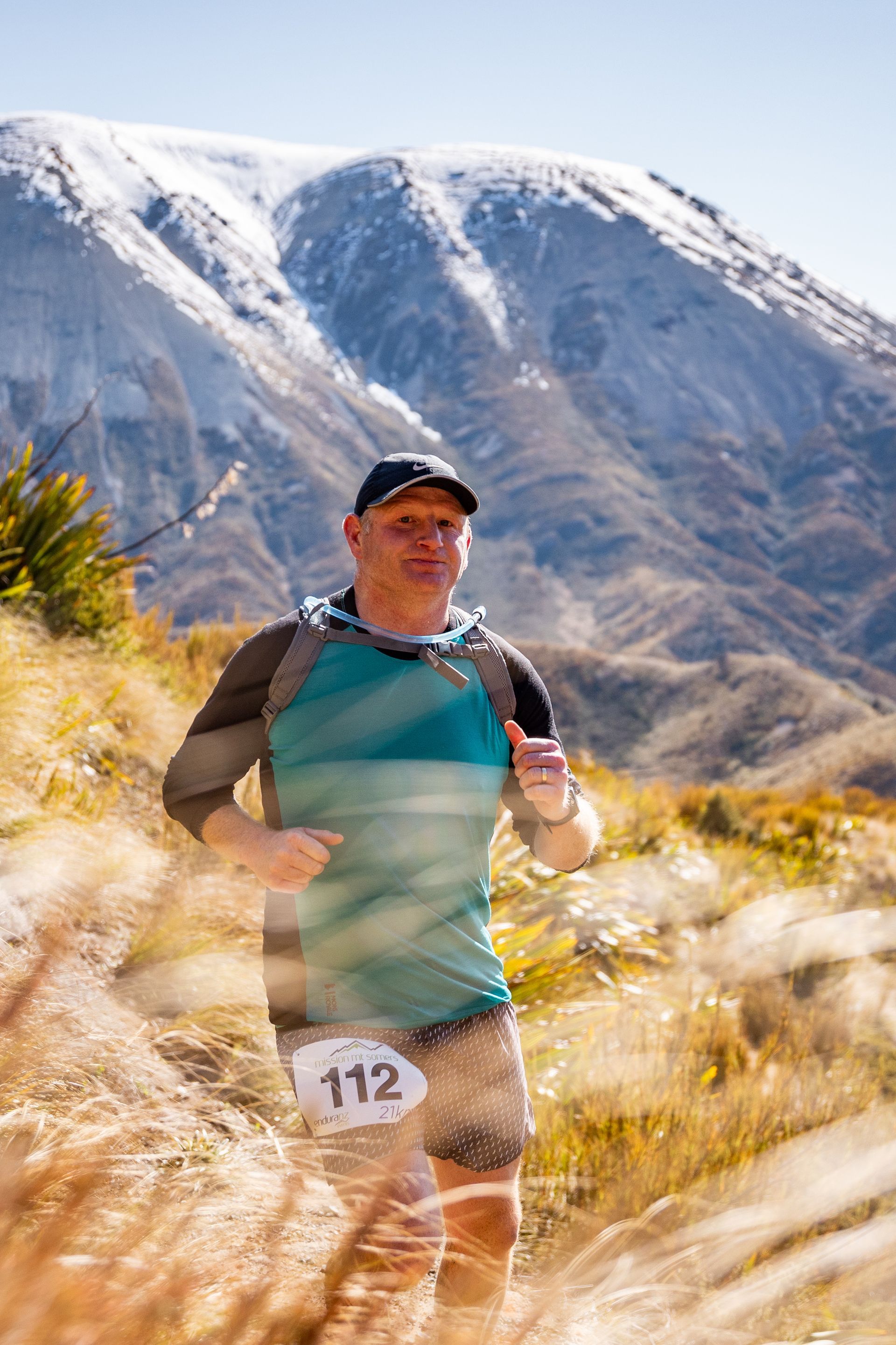 A man is running on a trail in front of a mountain.