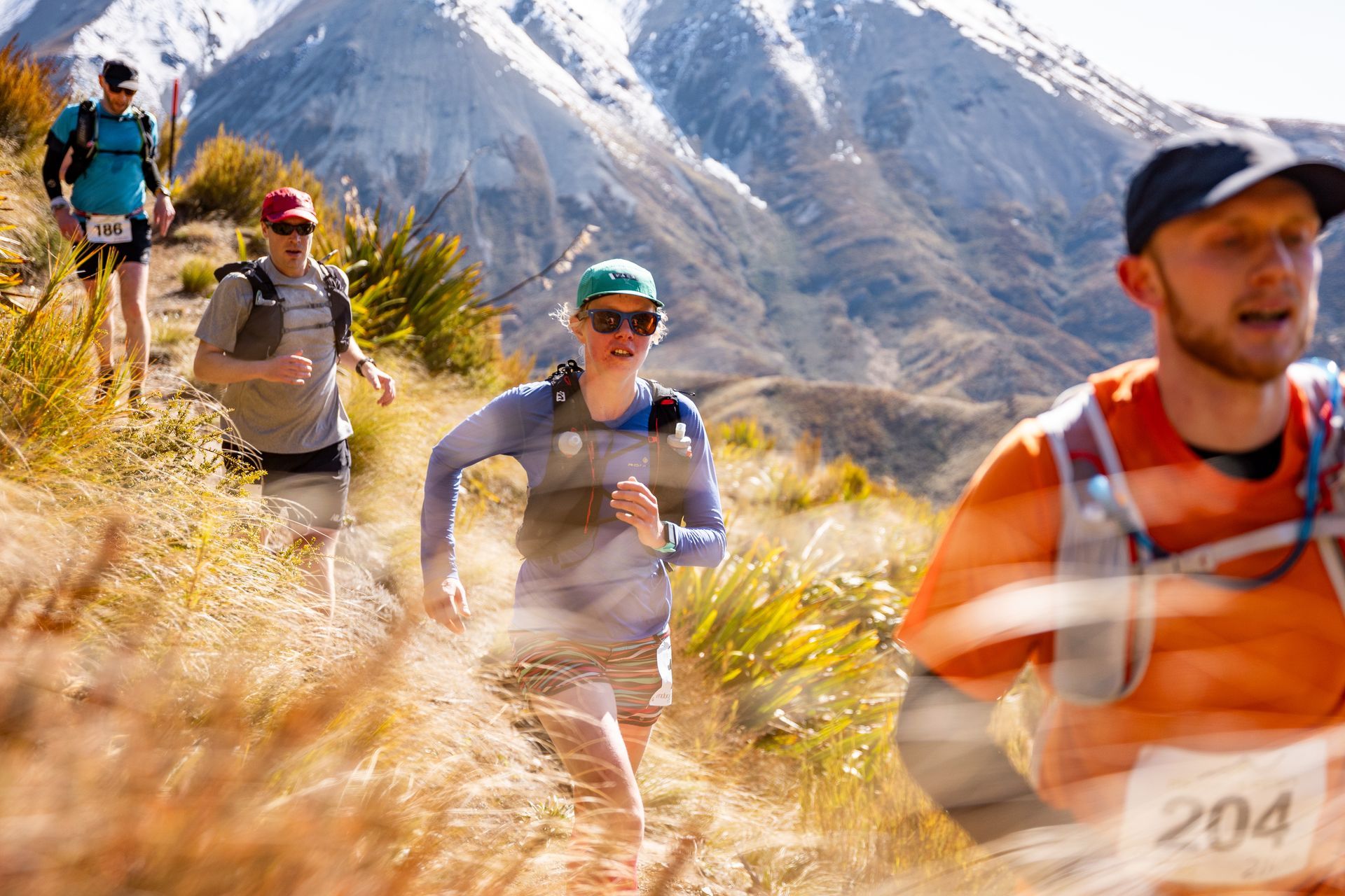 A group of people are running on a trail in the mountains.