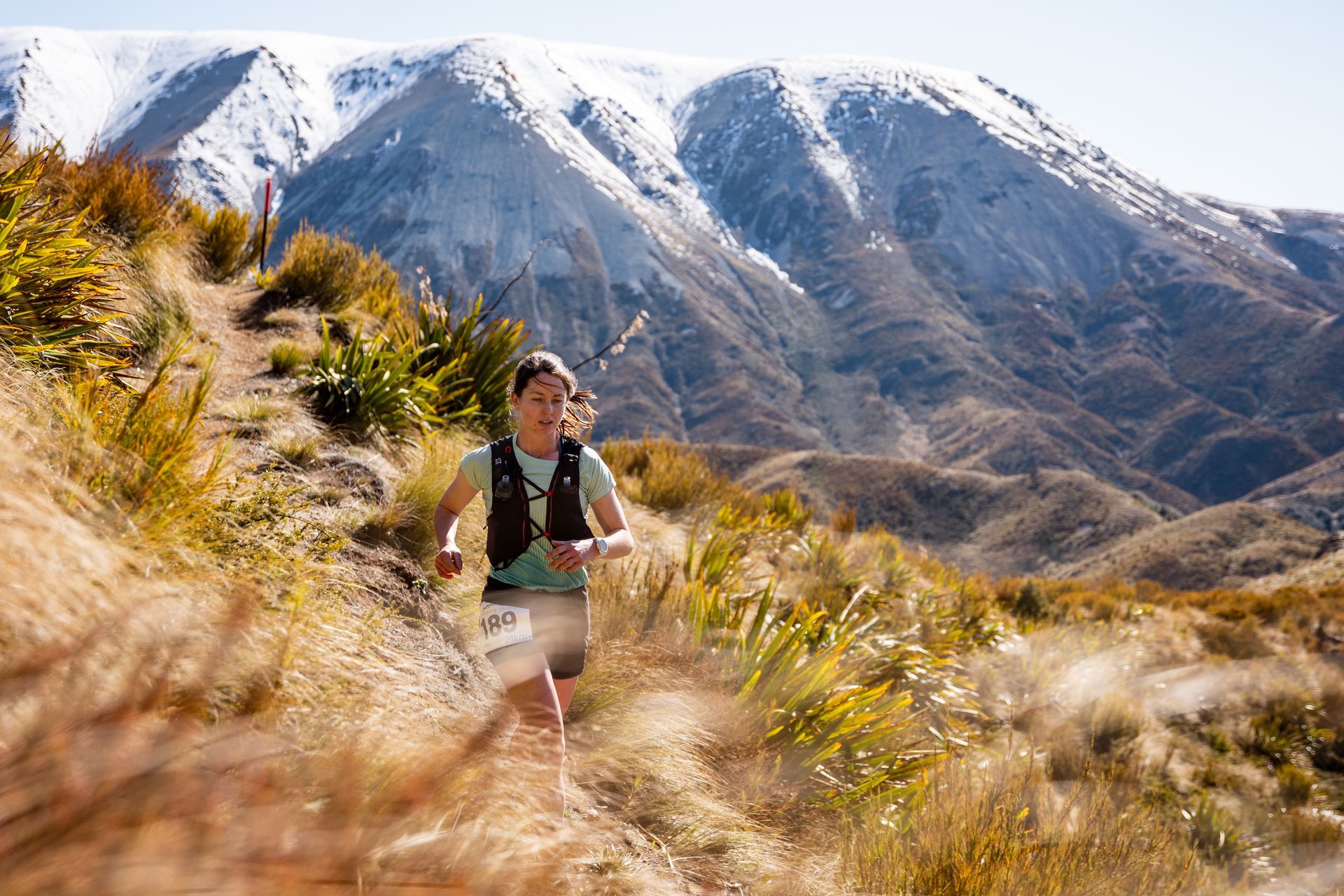 A woman is running on a trail in the mountains.