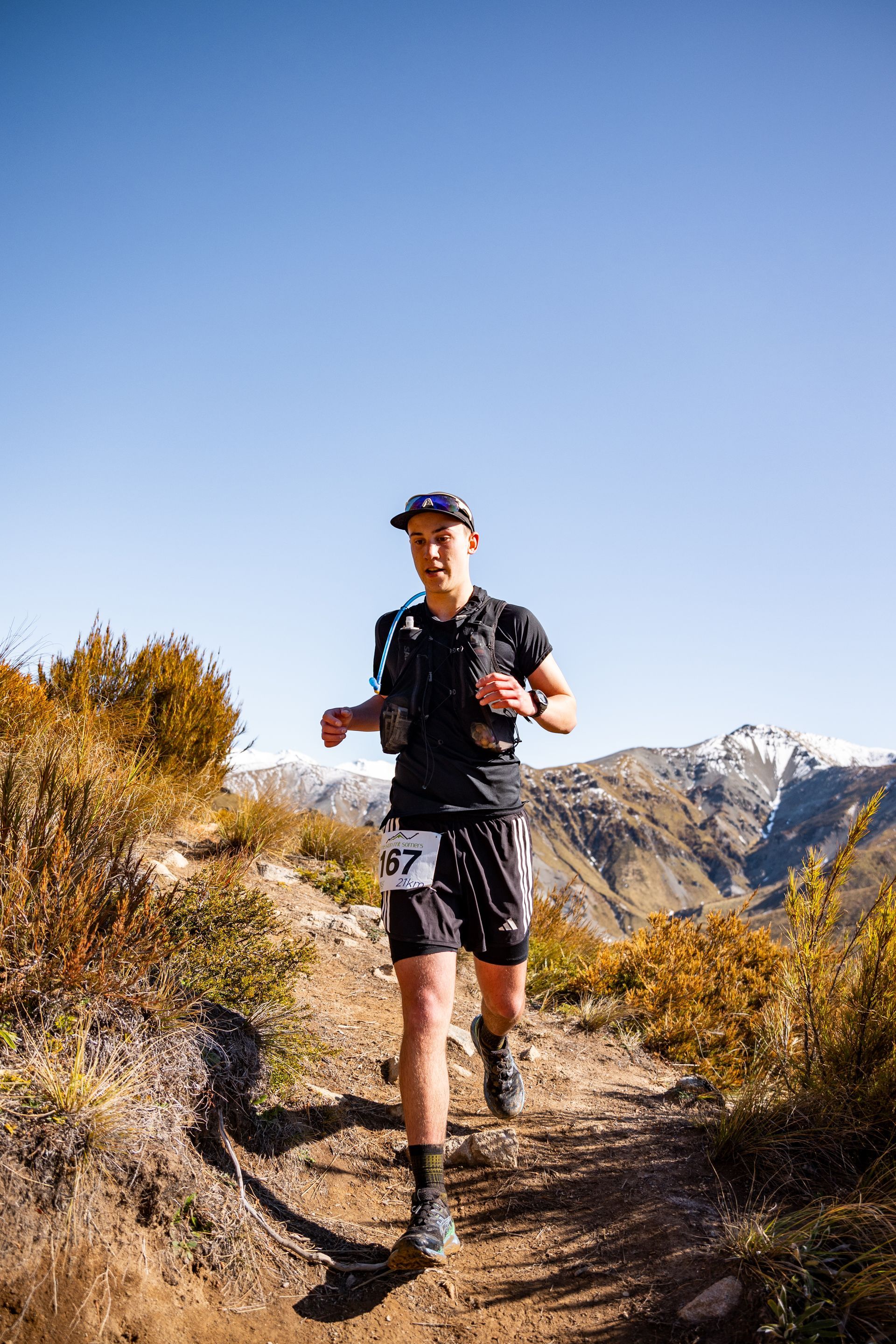 A man is running on a trail in the mountains.