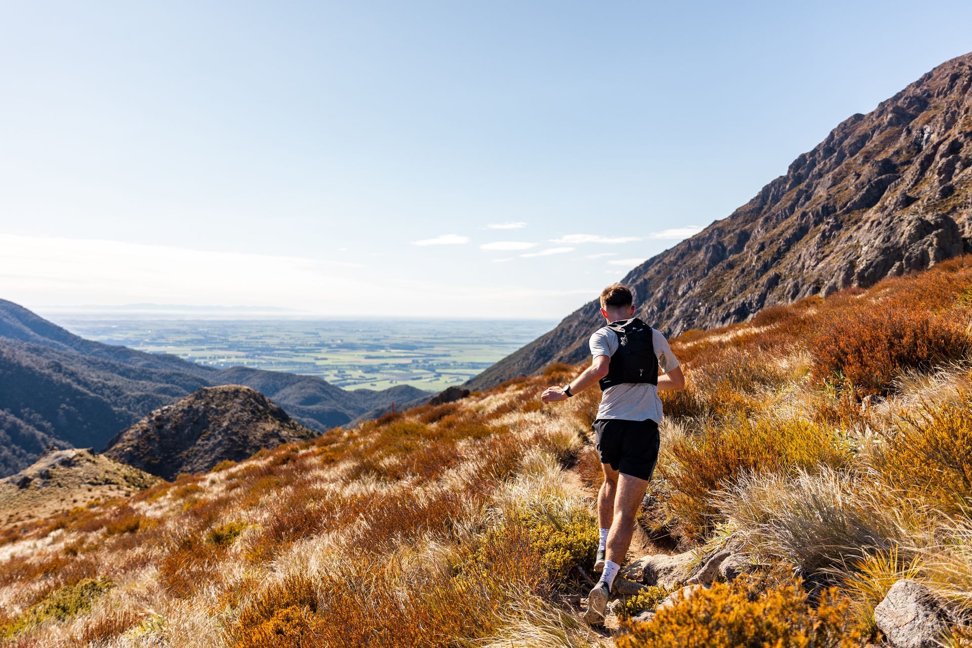 A man is running up a hill in the mountains.