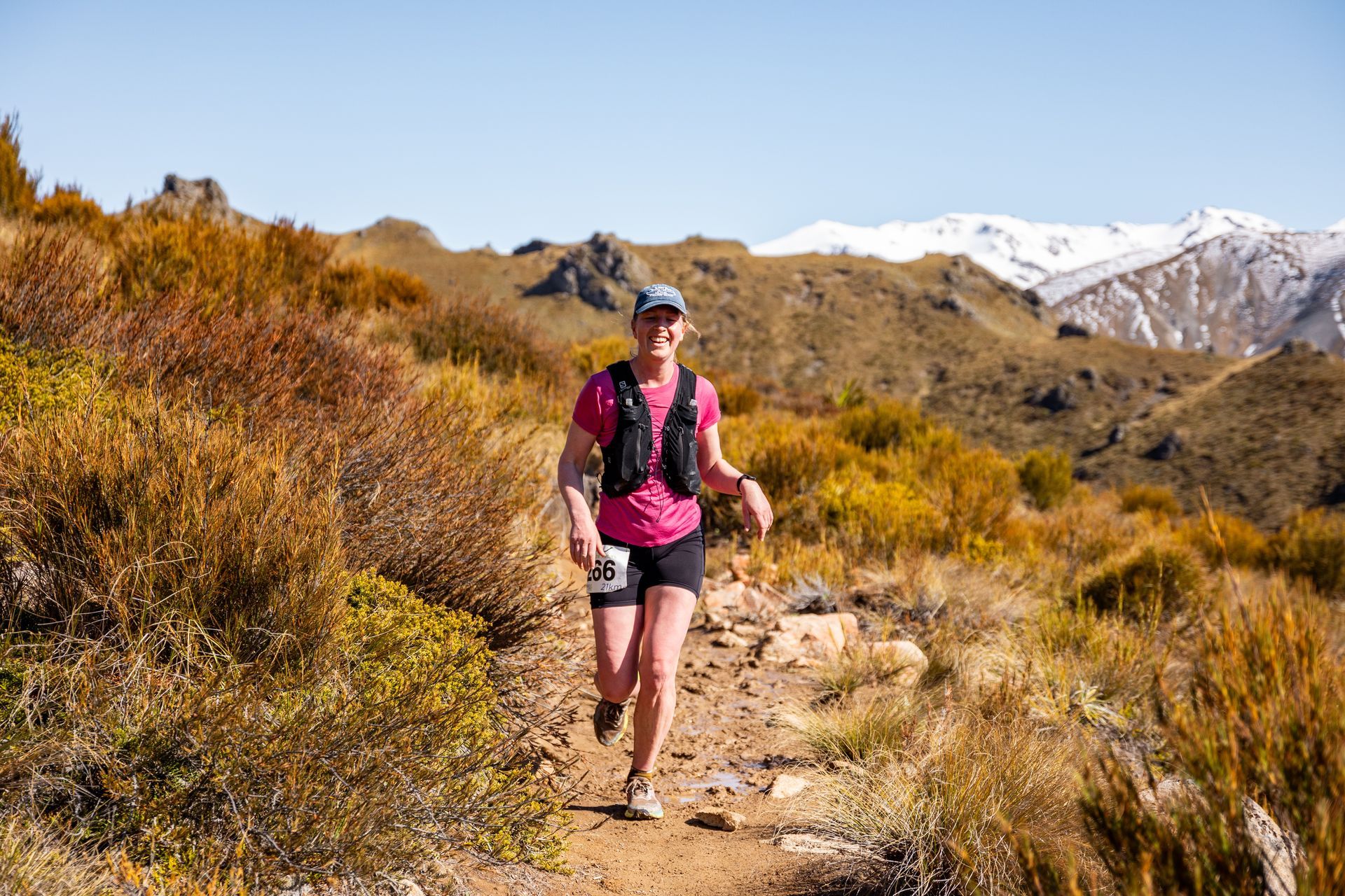A woman is running on a trail in the mountains.