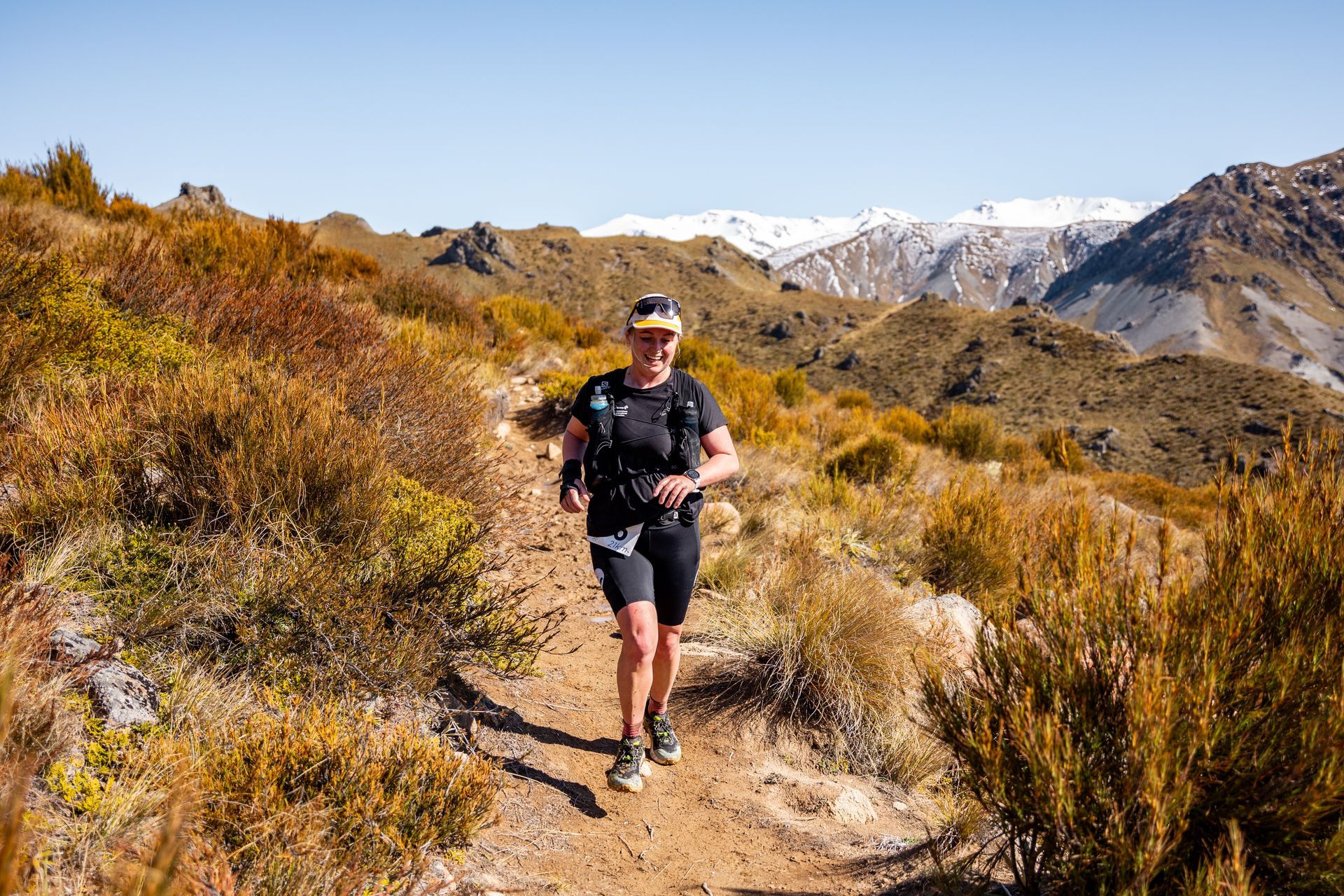 A man is running on a dirt trail in the mountains.