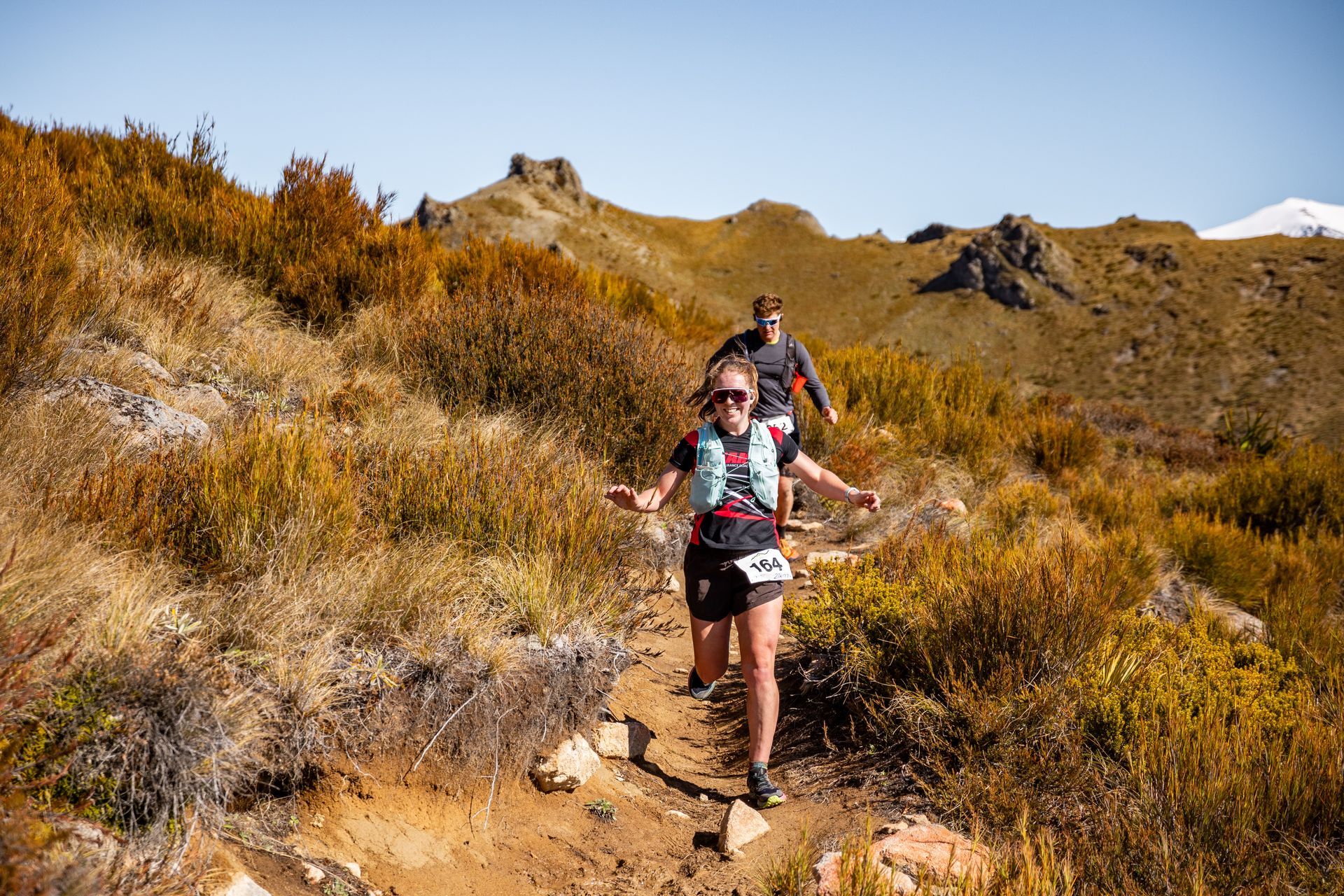 A group of people are running on a trail in the mountains.