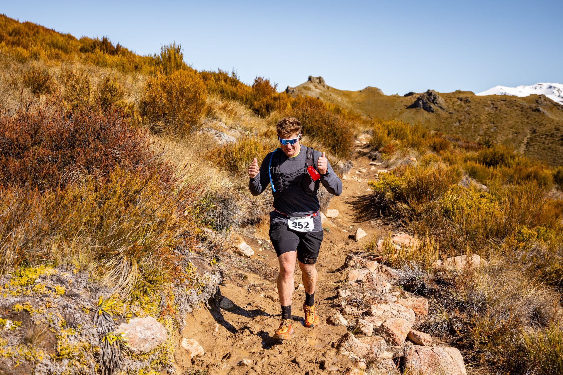 A man is running down a dirt trail in the mountains.