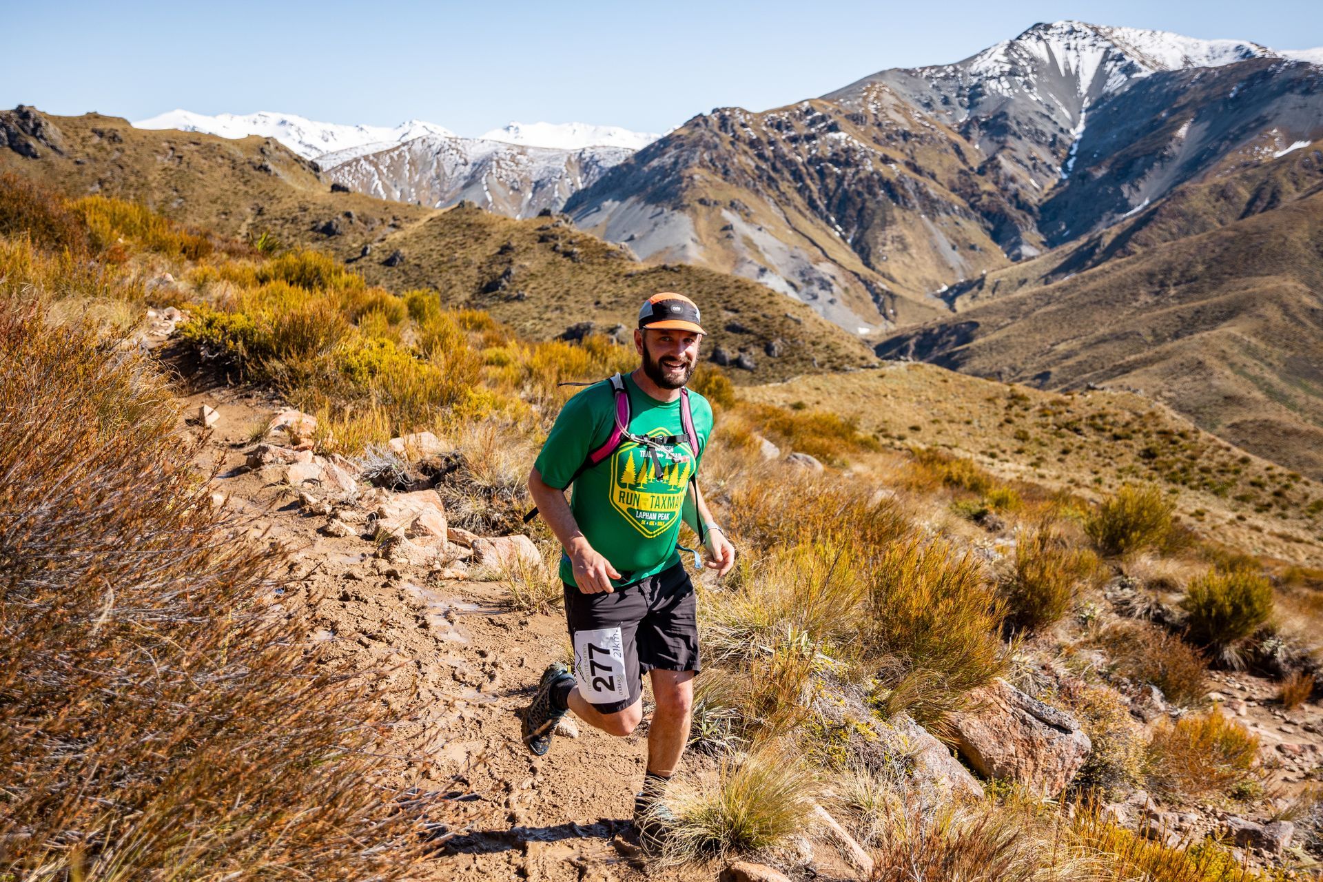 A man is running on a trail in the mountains.