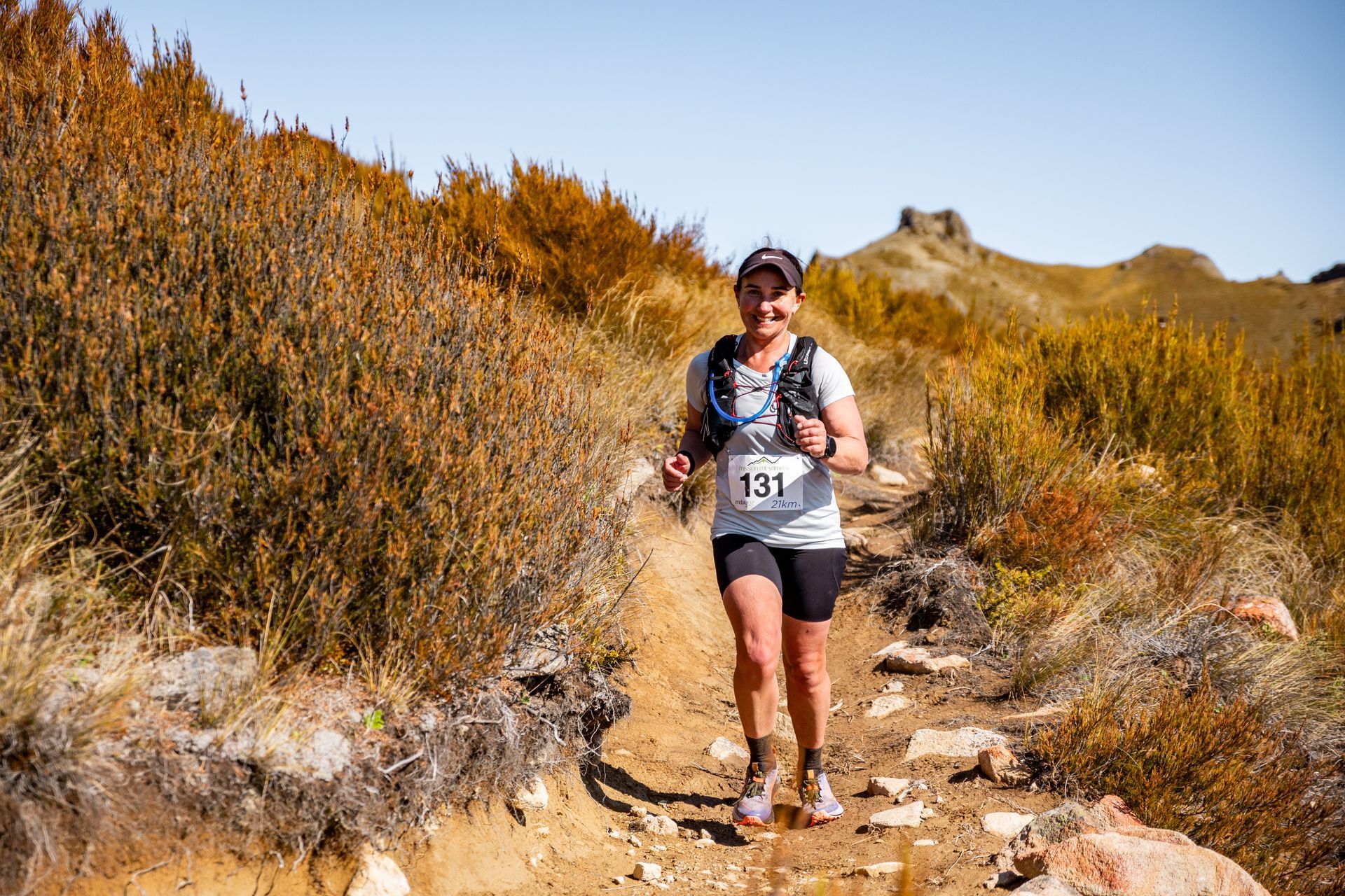 A woman is running on a dirt path in the mountains.