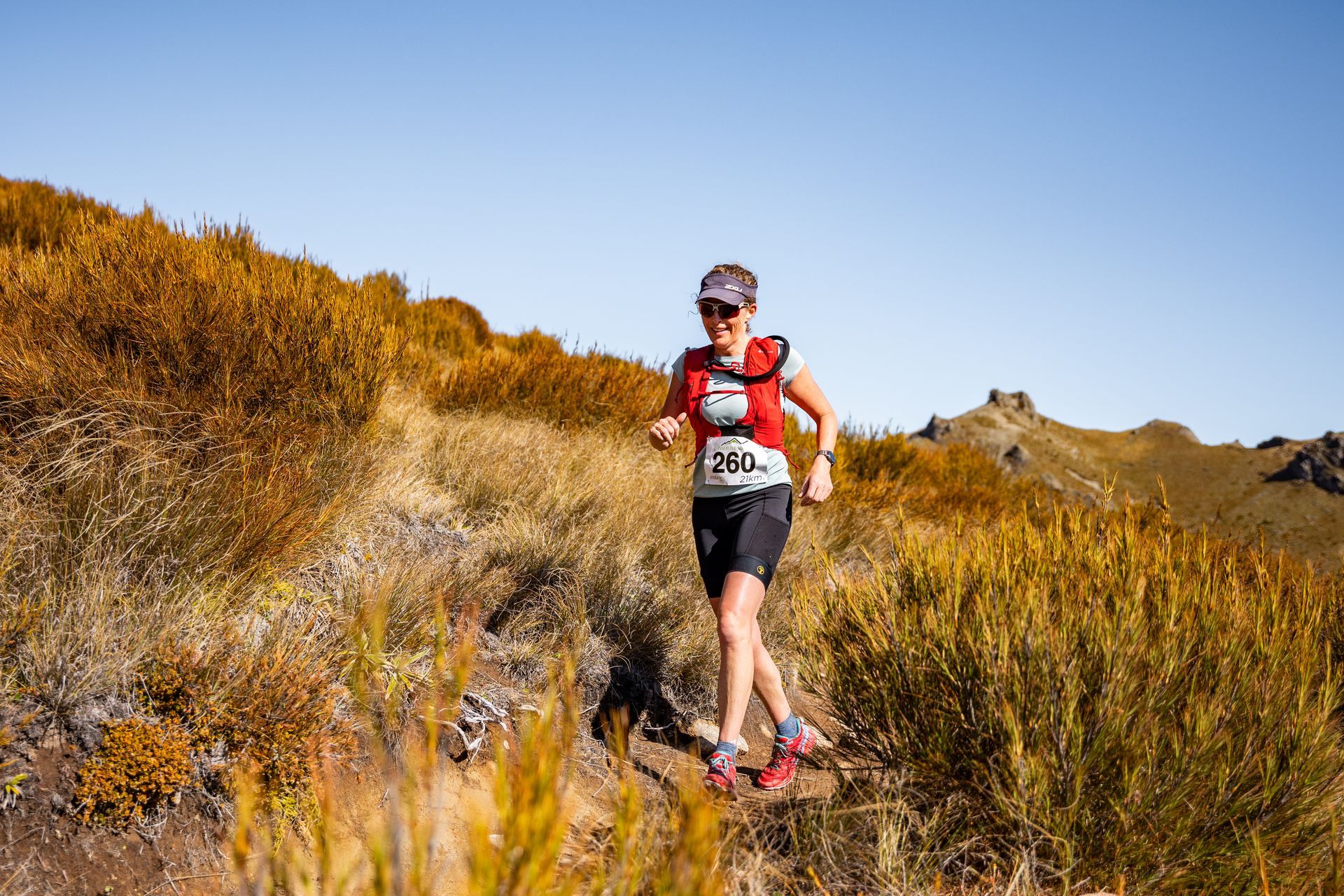 A woman is running on a trail in the mountains.