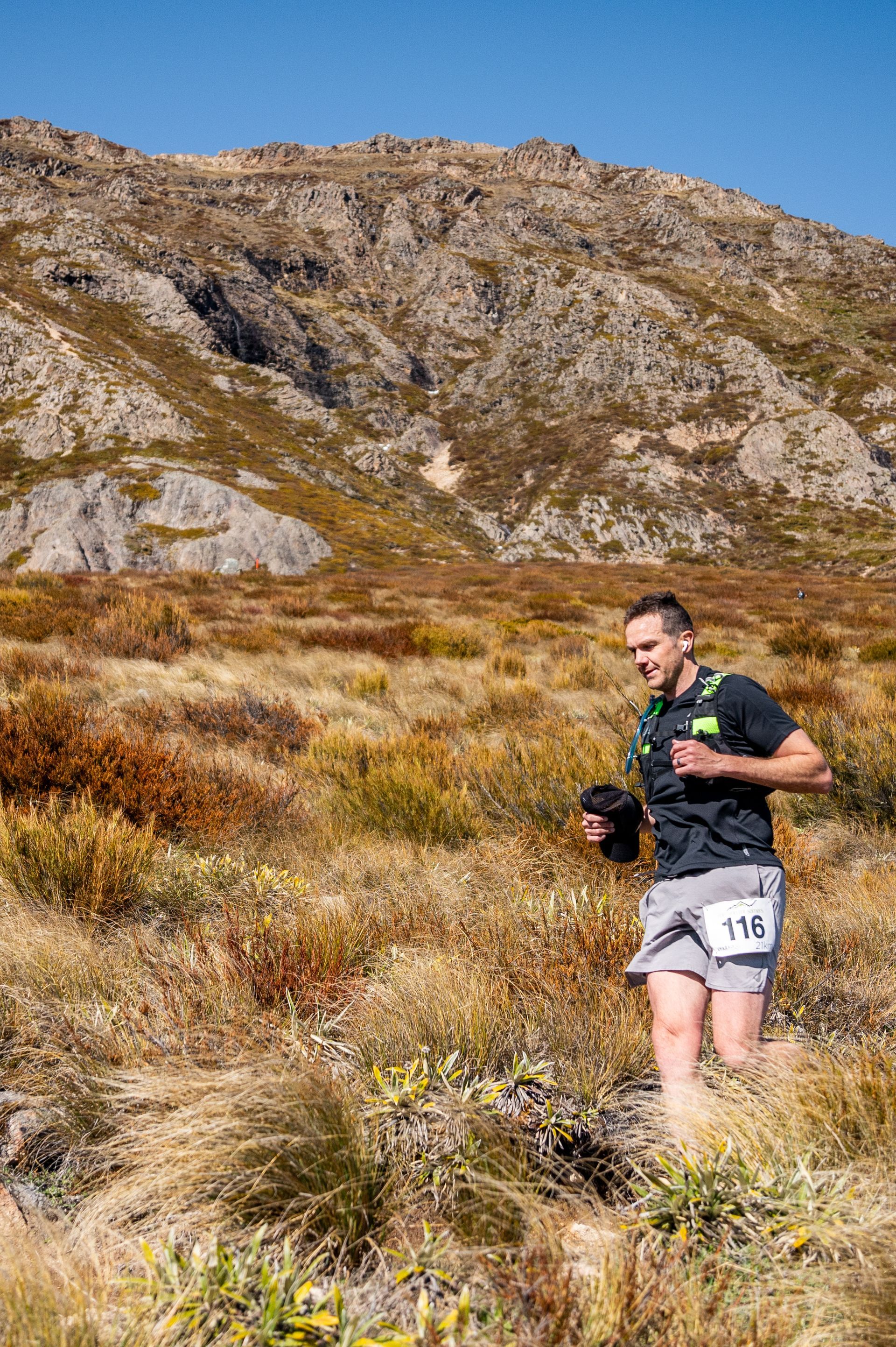 A man is running in a field with a mountain in the background.