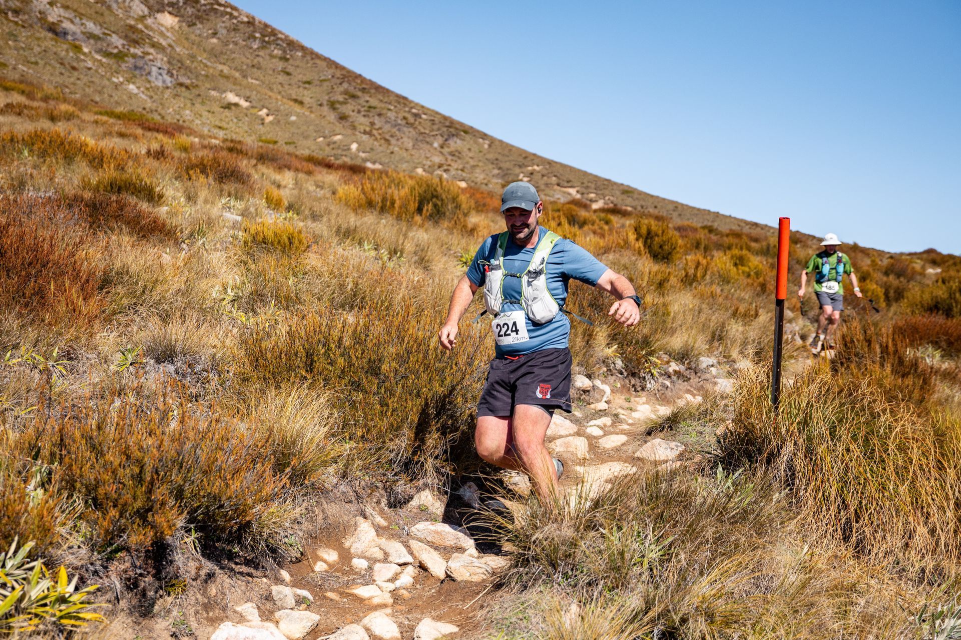A man is running on a trail in the mountains.