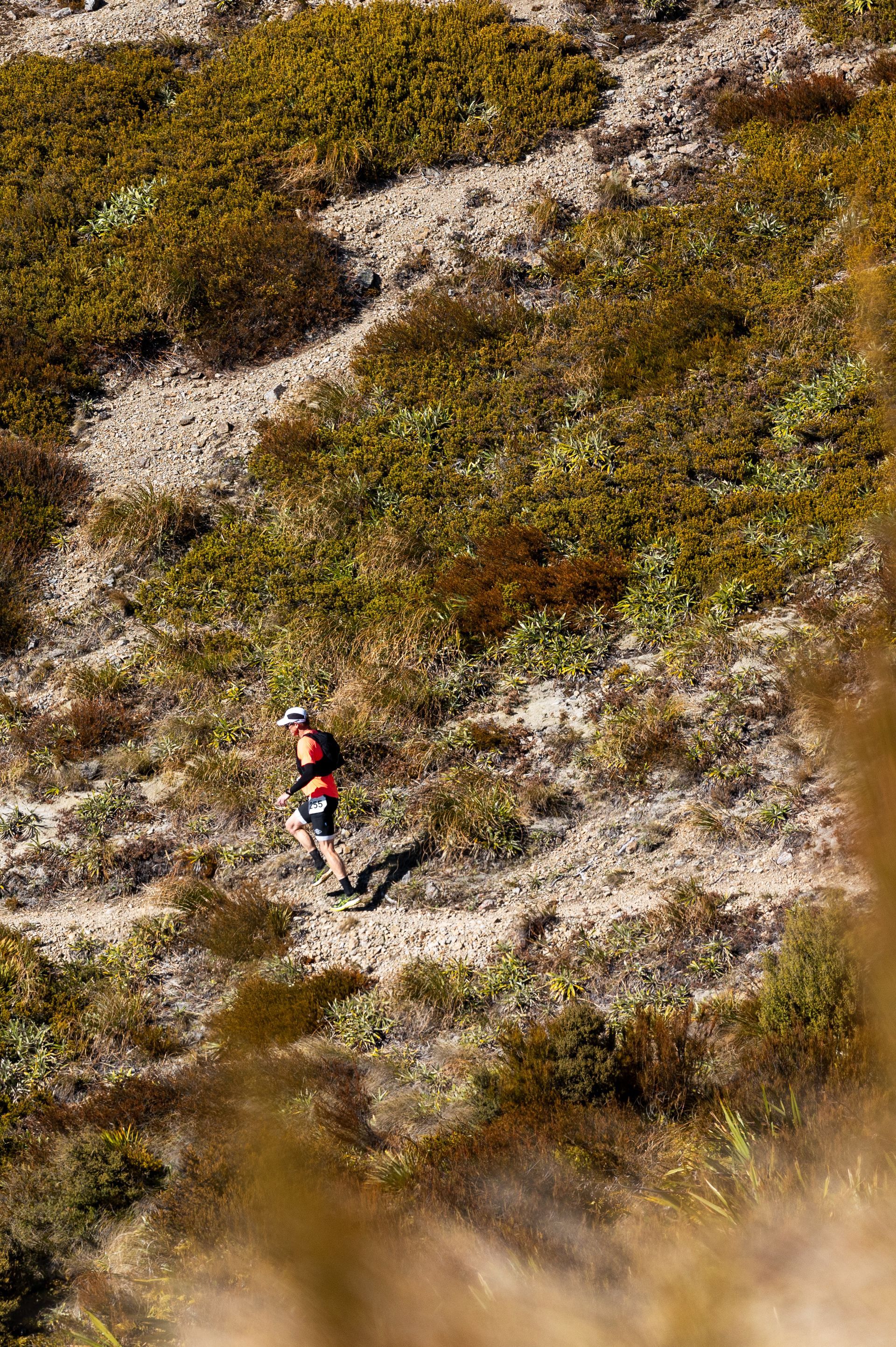 A man is running down a dirt path in the mountains.
