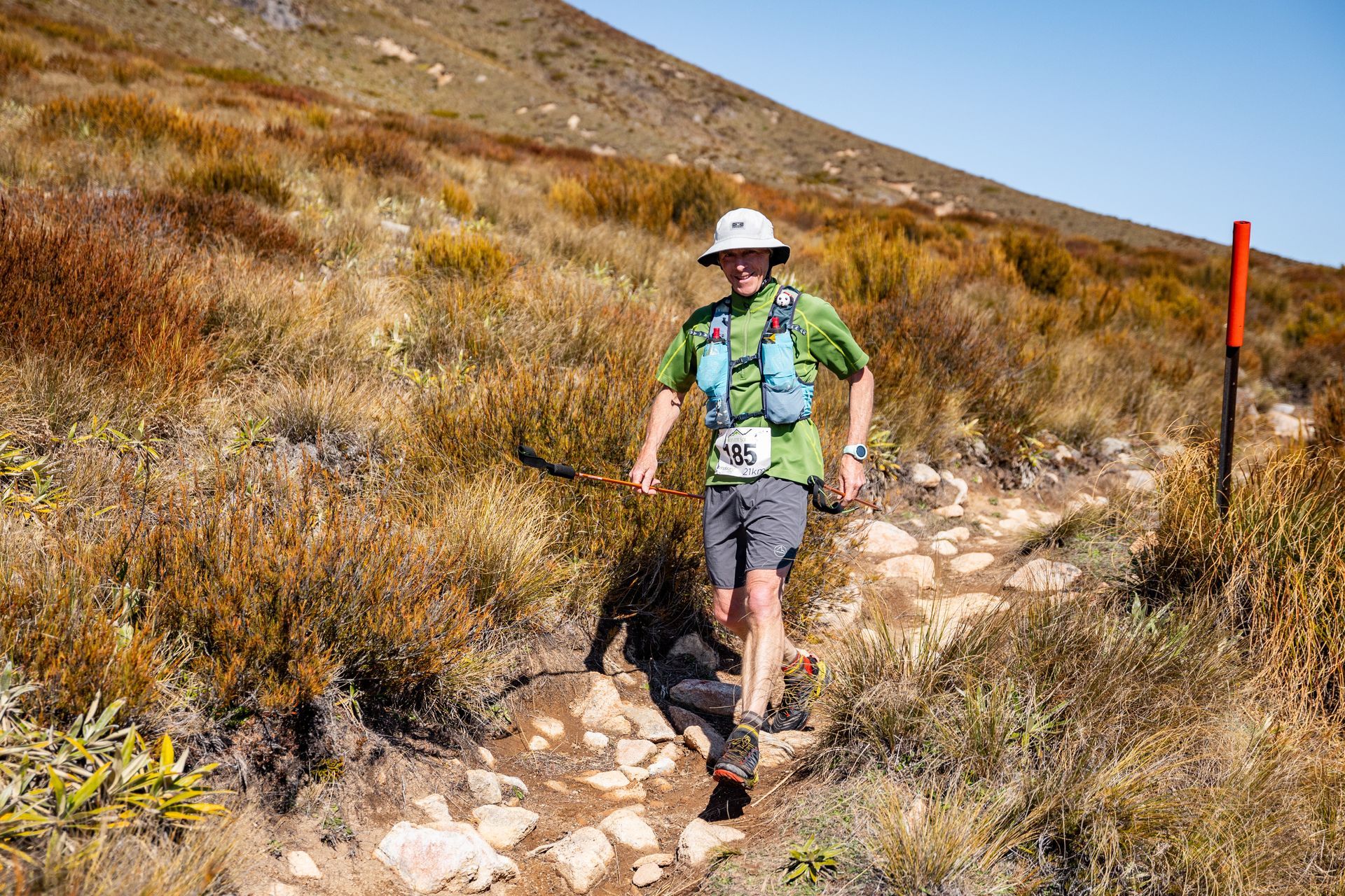 A man is running on a trail in the mountains.