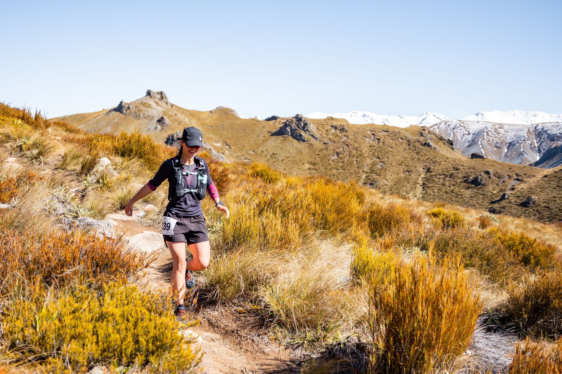 A woman is running on a trail in the mountains.