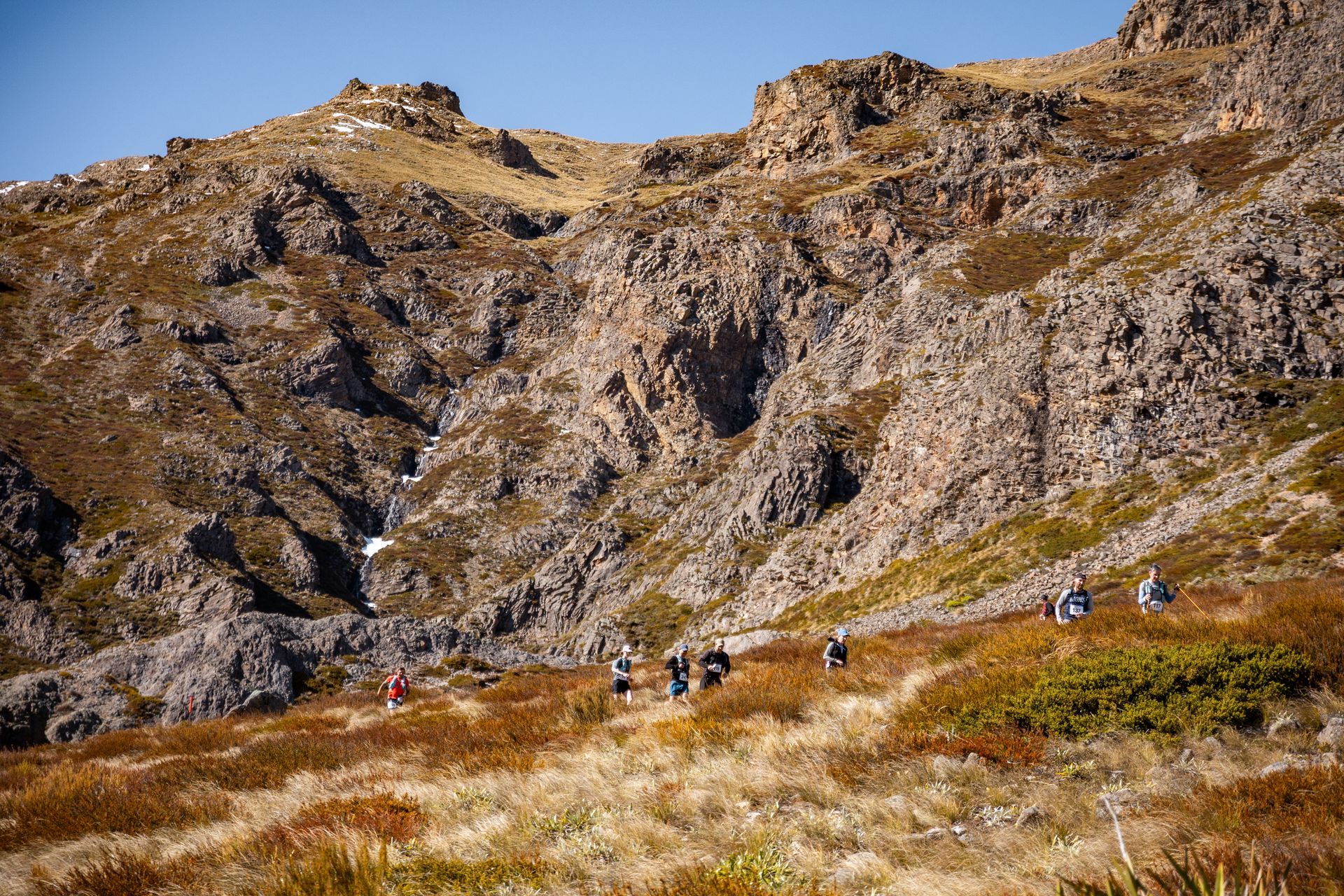 A group of people are walking on a trail in the mountains.