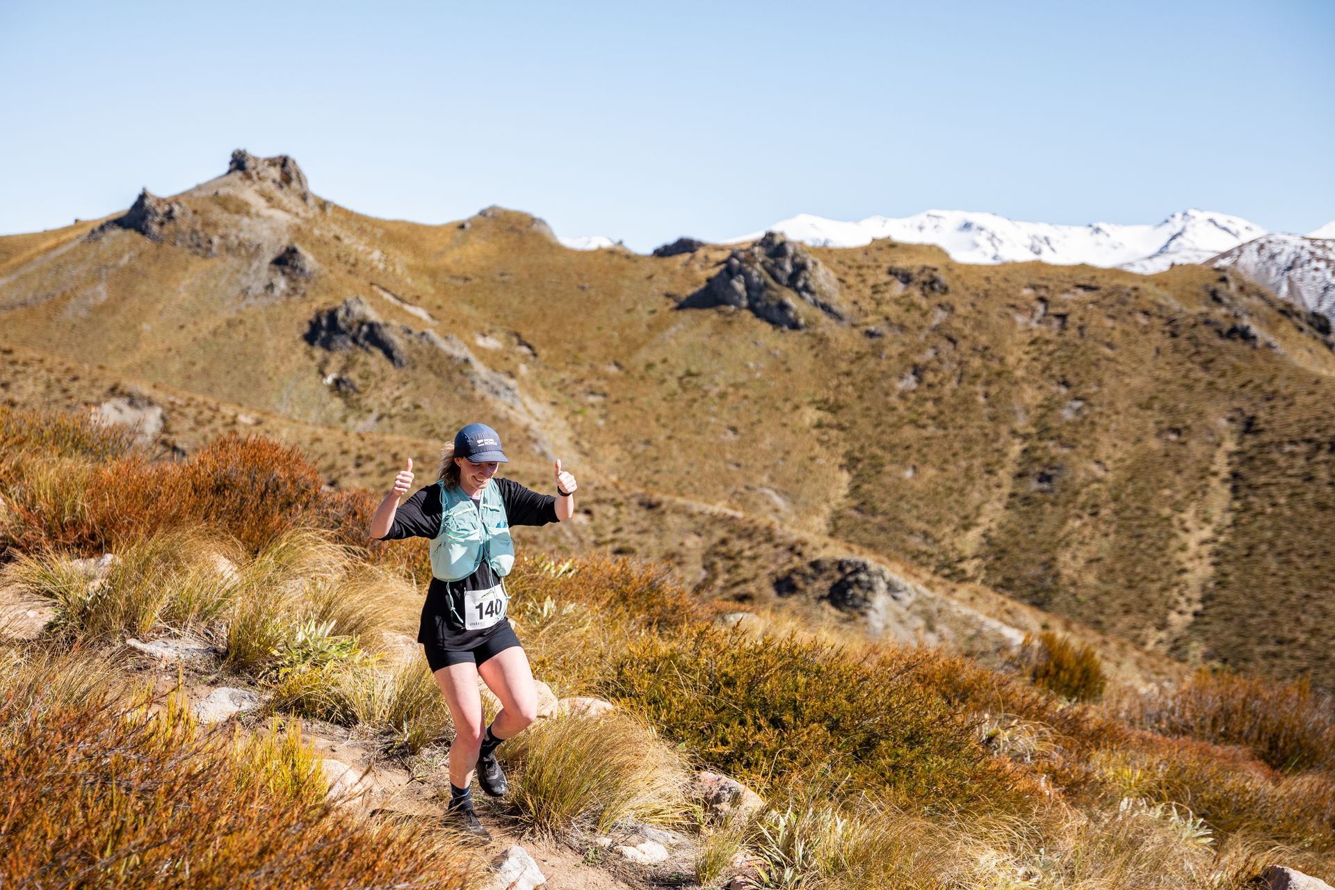 A woman is running on a trail in the mountains.