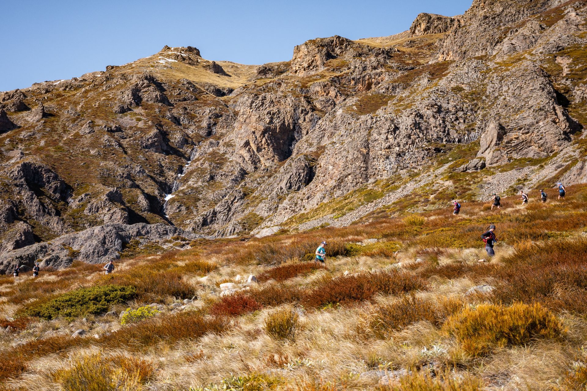 A group of people are hiking up a hill in the mountains.