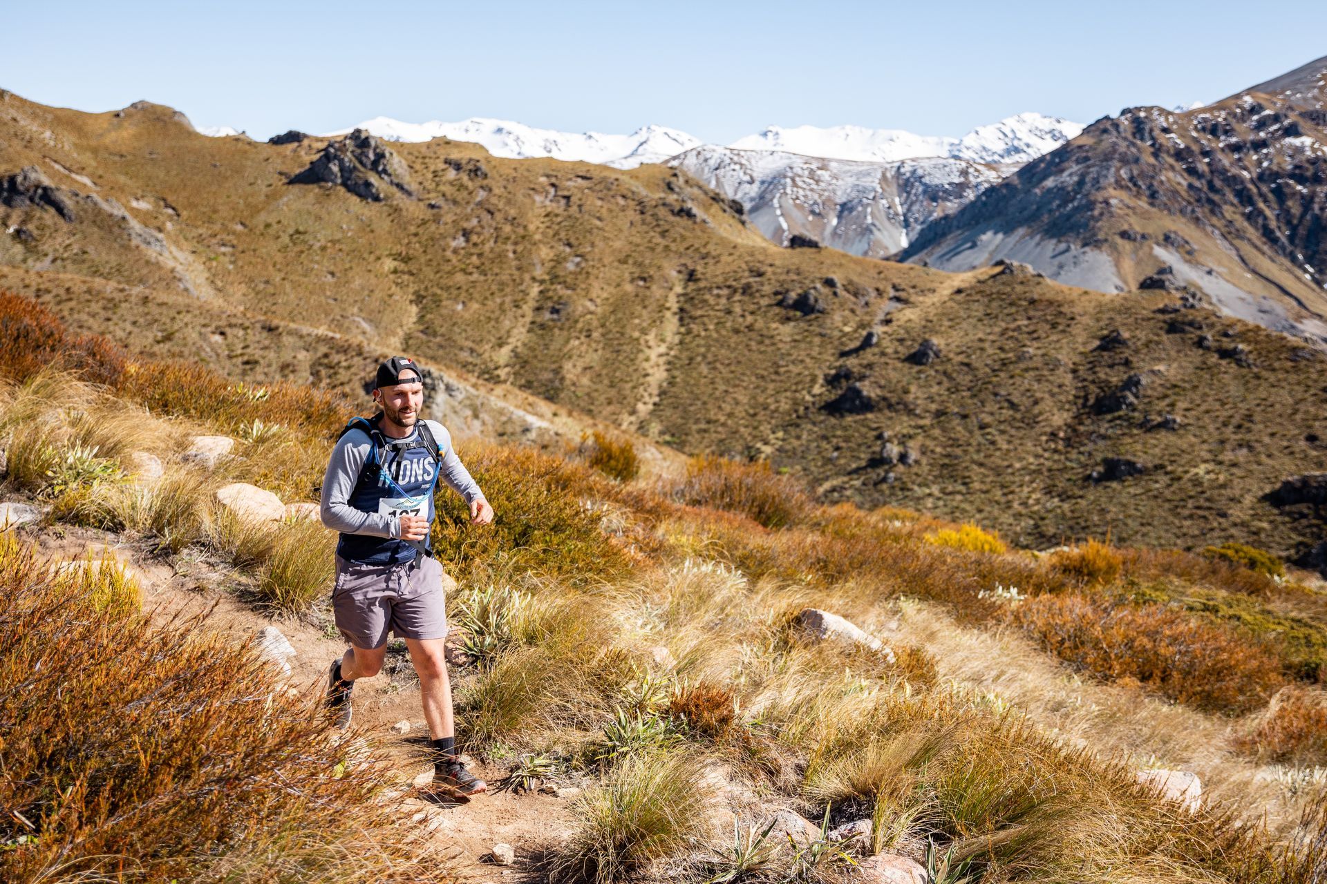 A man is running on a trail in the mountains.