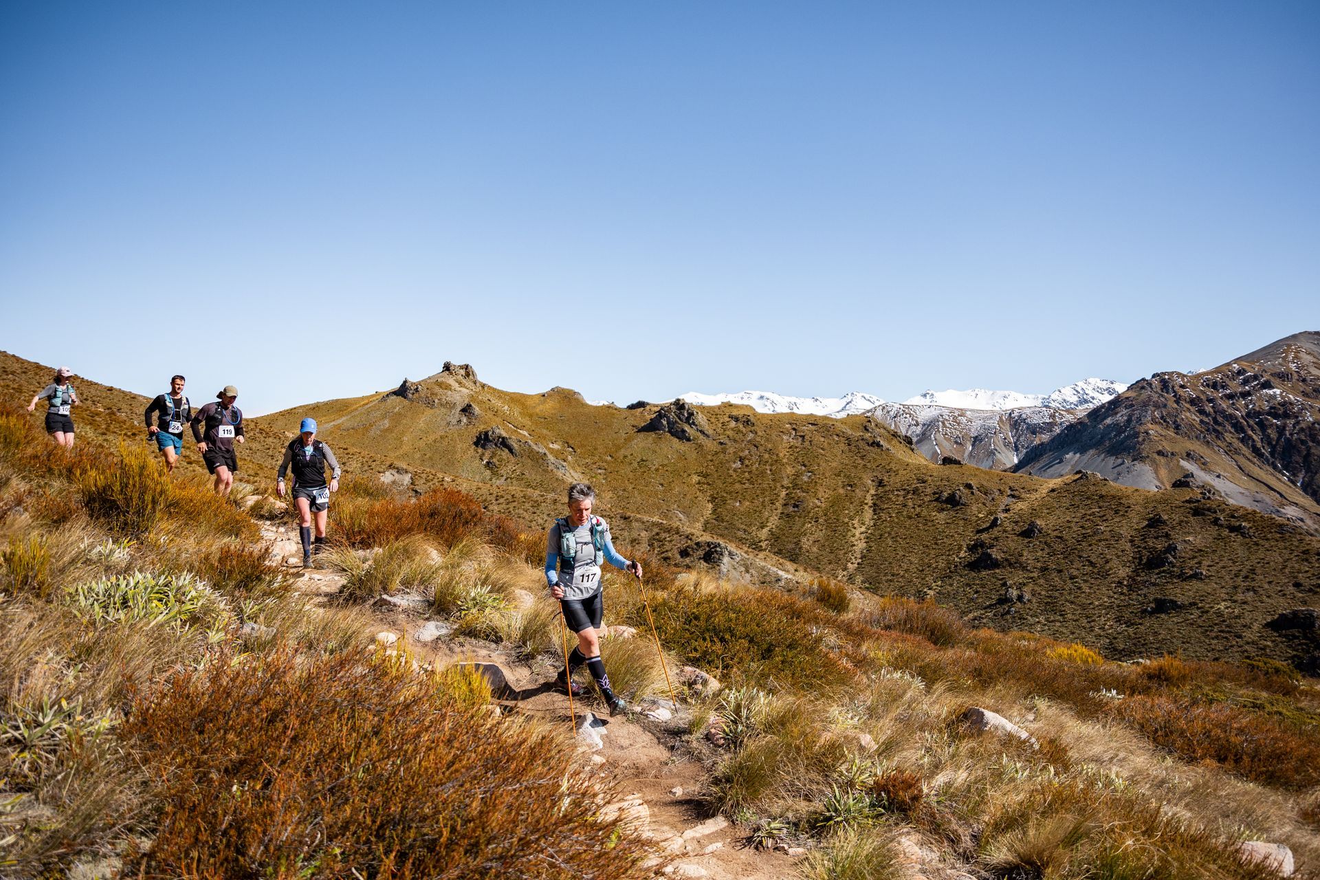A group of people are running on a trail in the mountains.