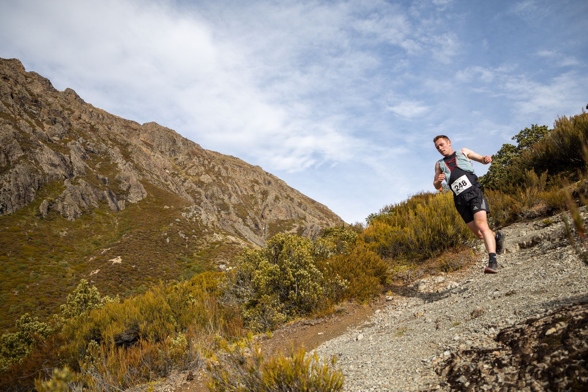 A man is running on a trail in the mountains.