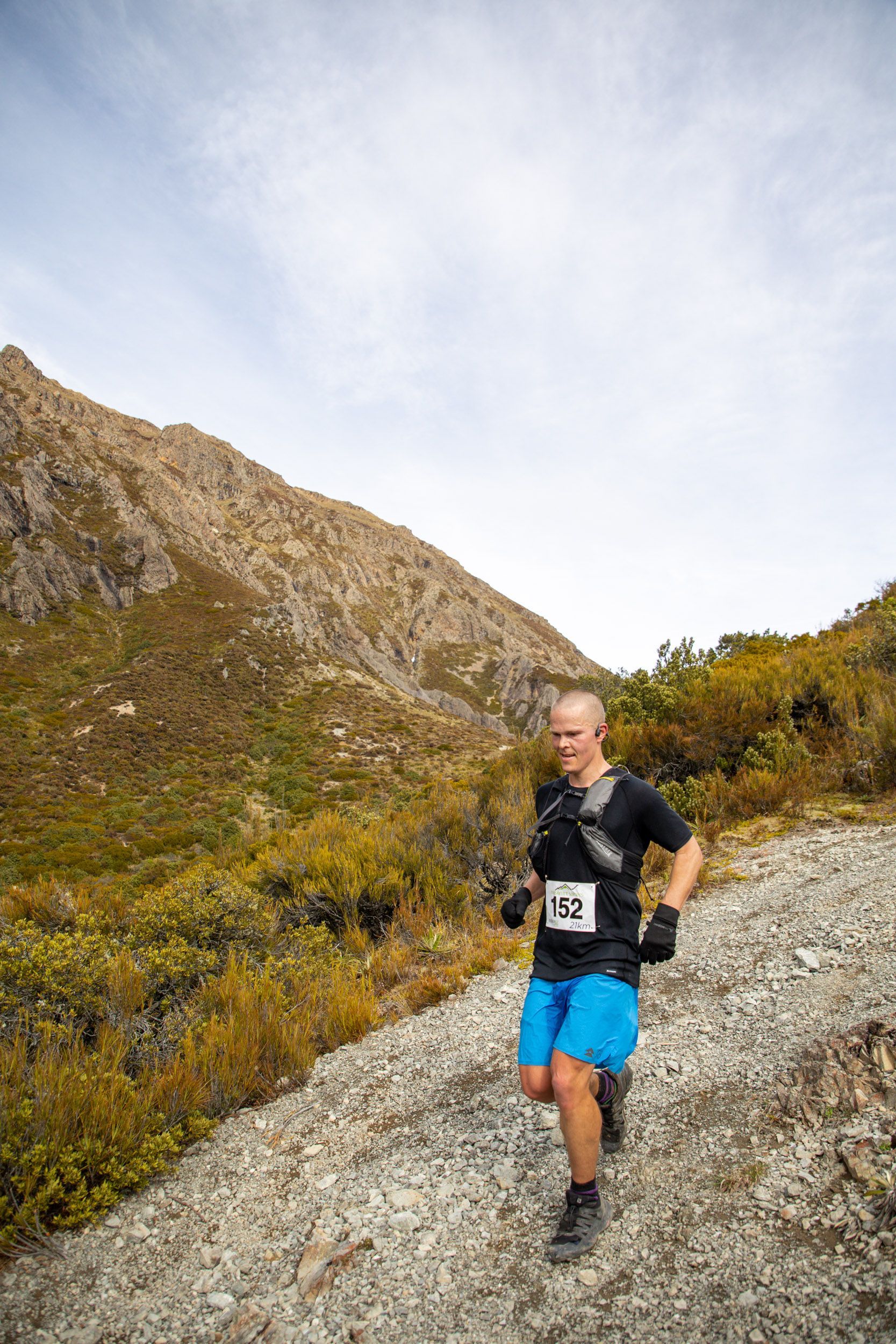 A man is running up a rocky hillside.