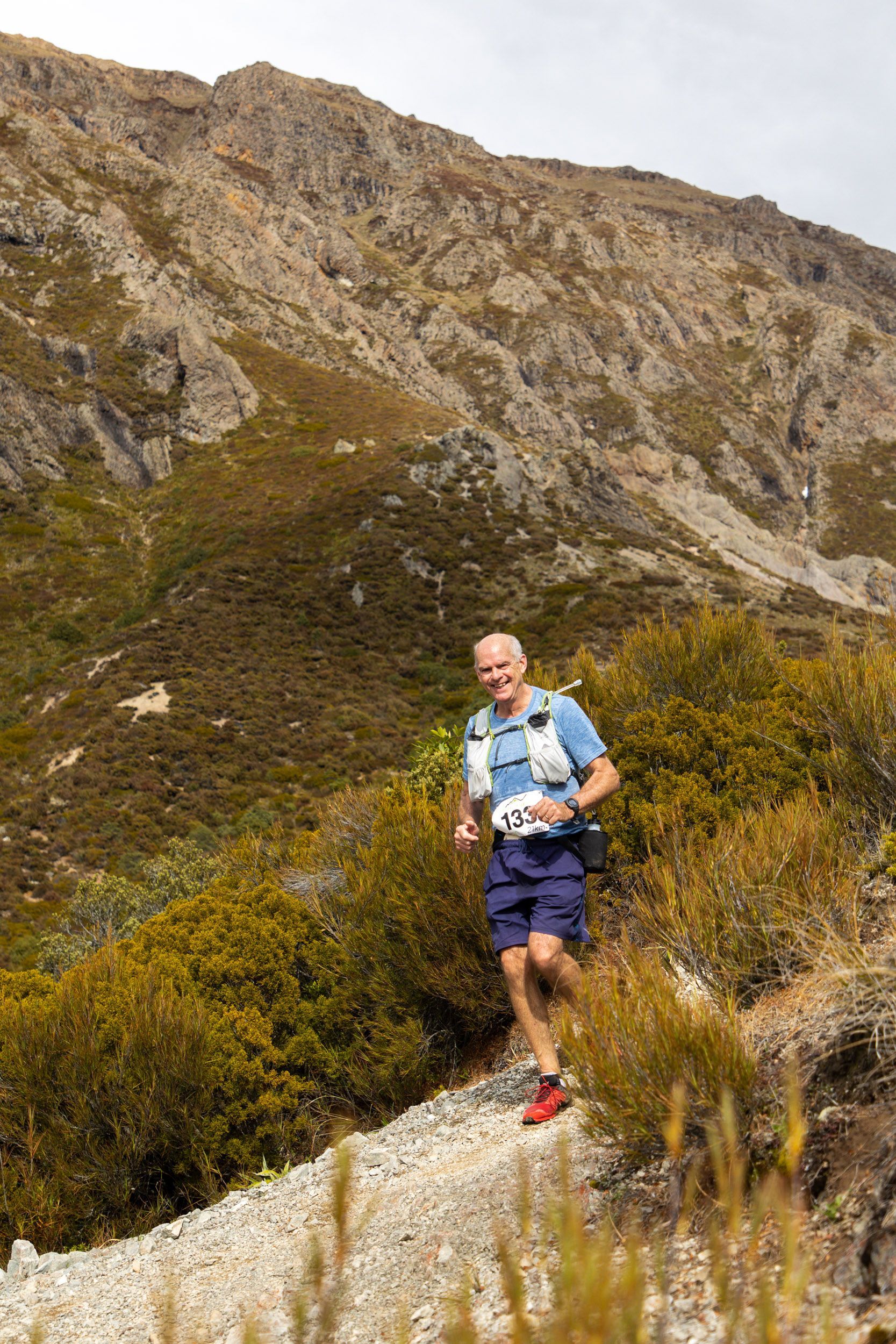 A man is running on a trail in the mountains.