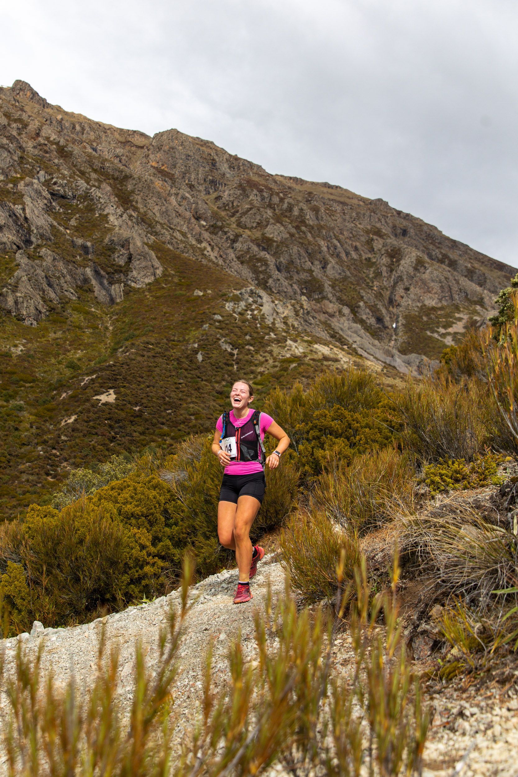 A woman is running on a trail in the mountains.