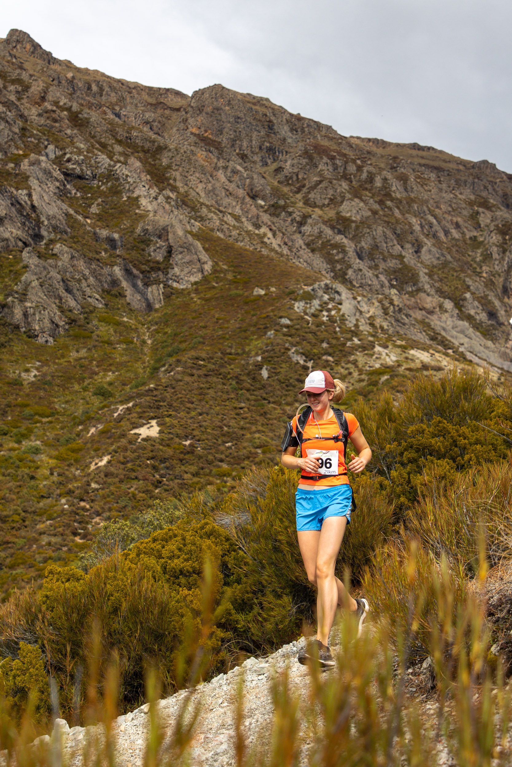 A woman is running on a trail in the mountains.