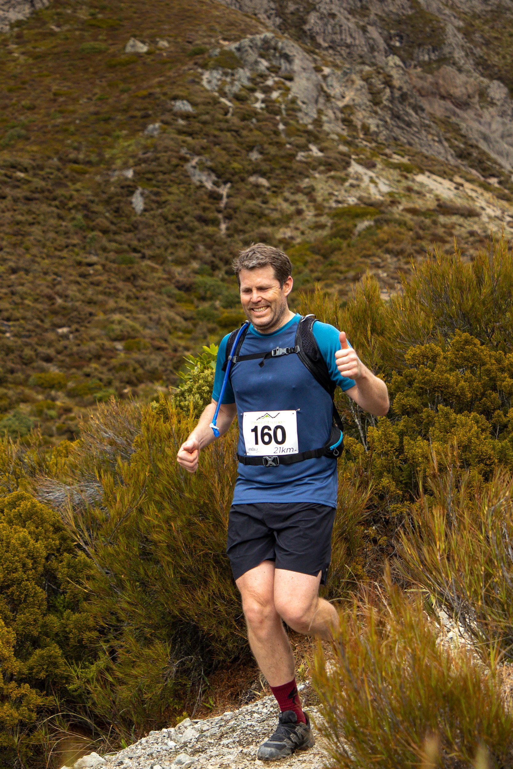 A man is running on a trail in the mountains.